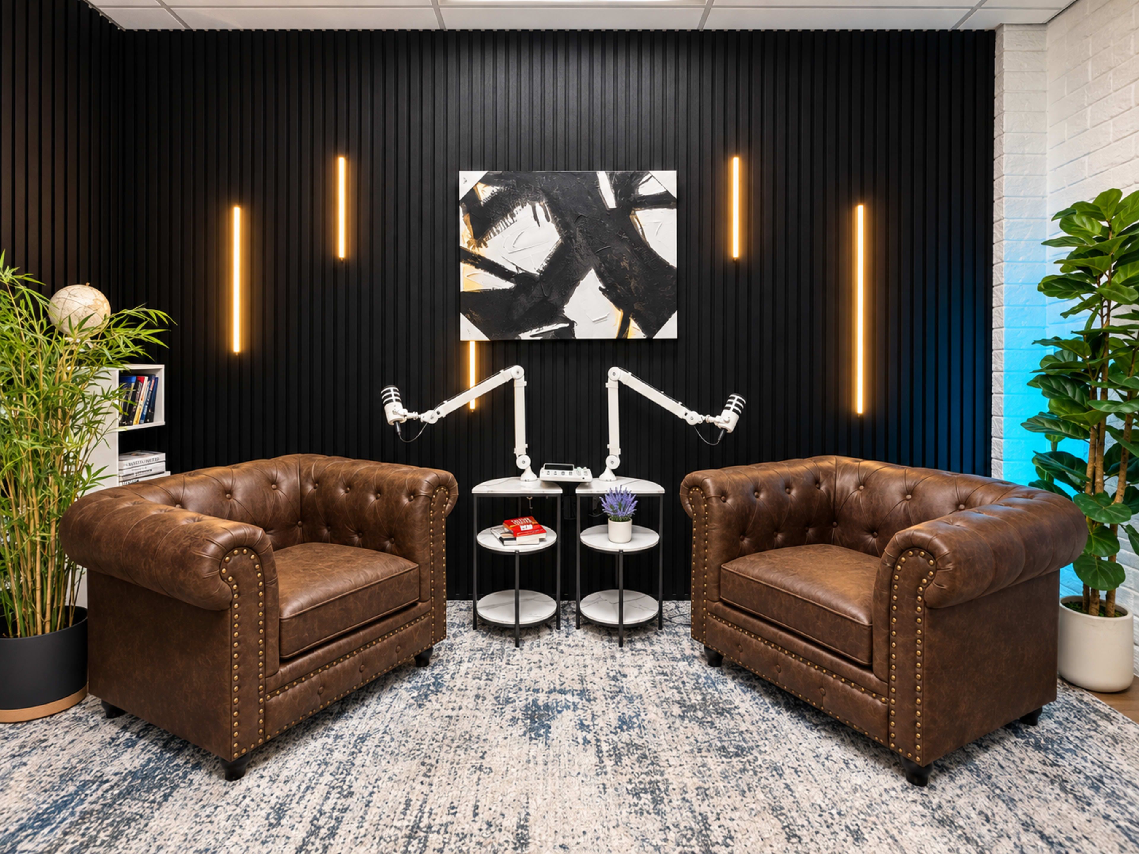 The image depicts a modern conversational area with two brown tufted leather armchairs, a circular side table between them, and a black wall adorned with vertical slats and recessed lighting.