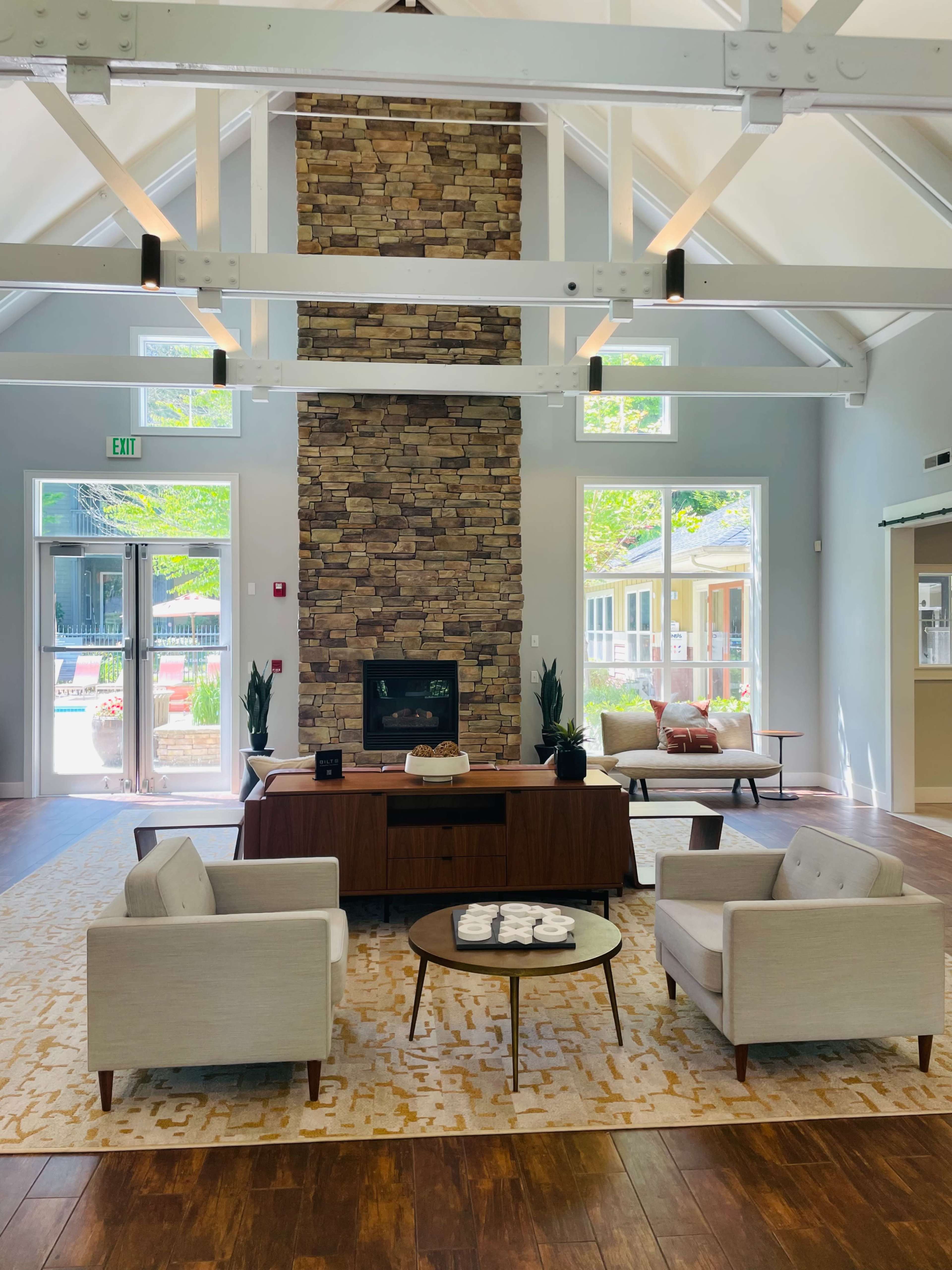 A spacious lobby features a stone fireplace, contemporary seating, and large windows allowing natural light.