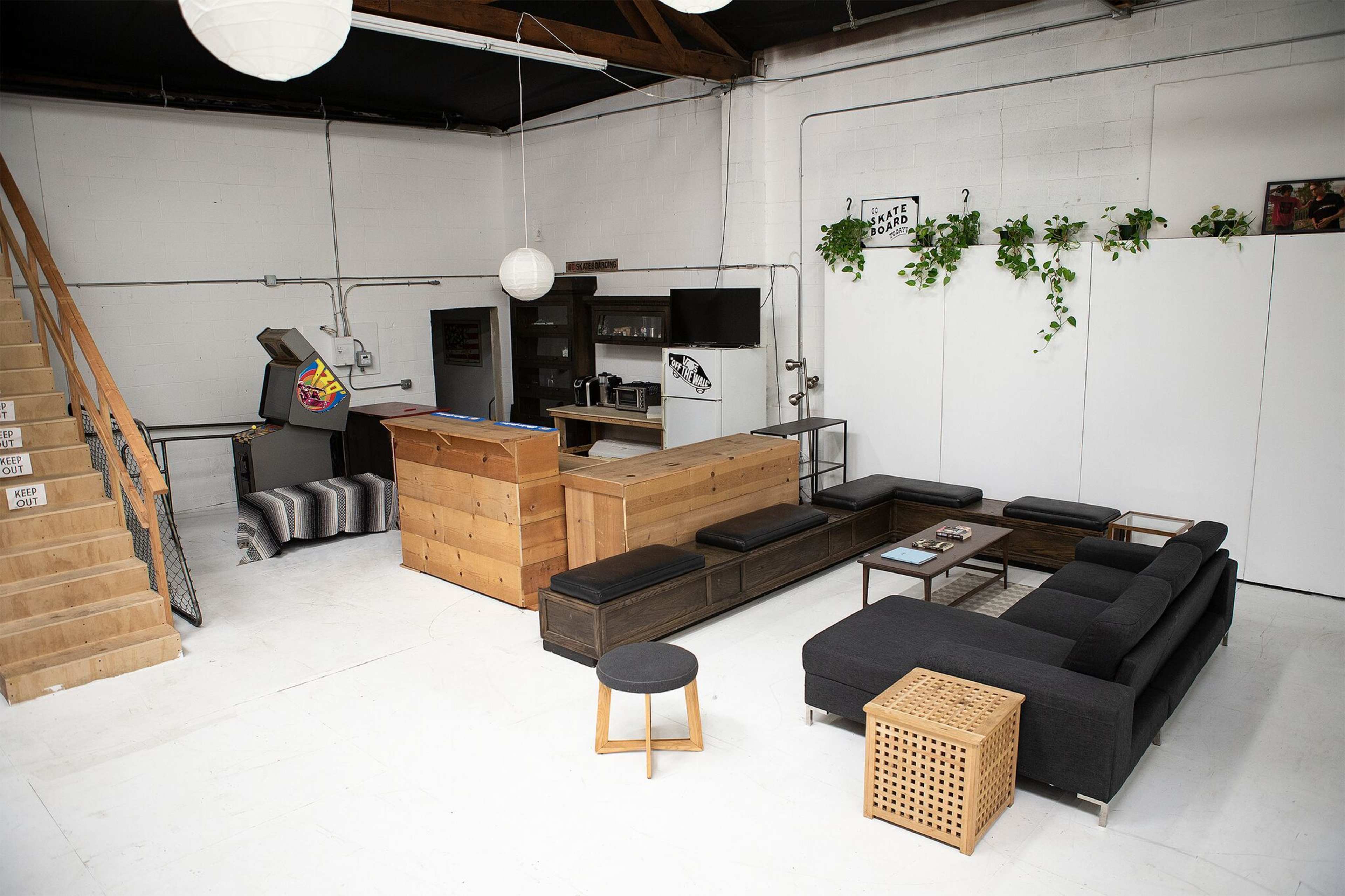 A modern, open-space interior with a wooden bar, seating area, and a staircase leading to a second level.