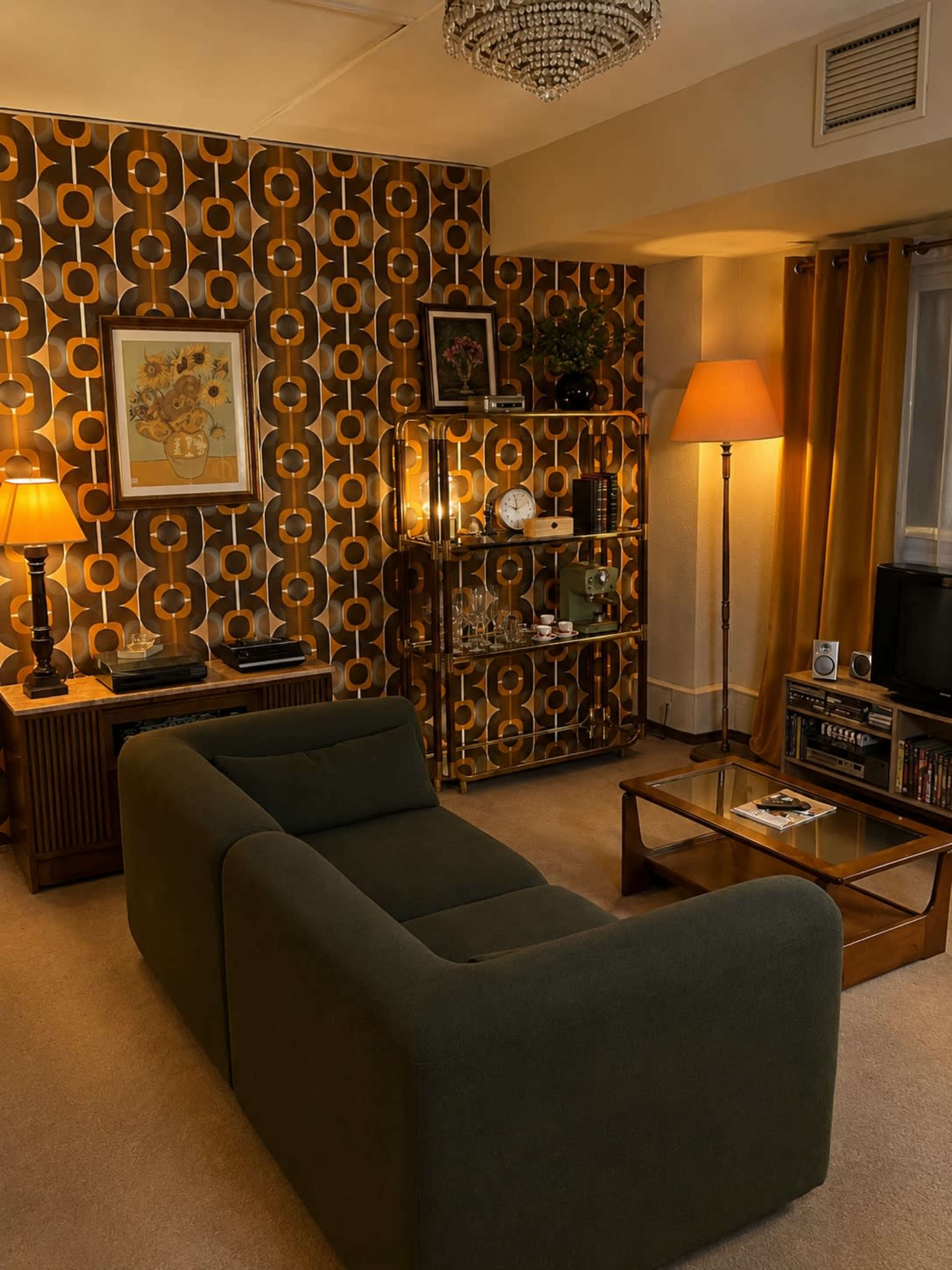 The image shows a cozy living room featuring a green sofa, a wooden coffee table, and retro wallpaper with circular patterns.
