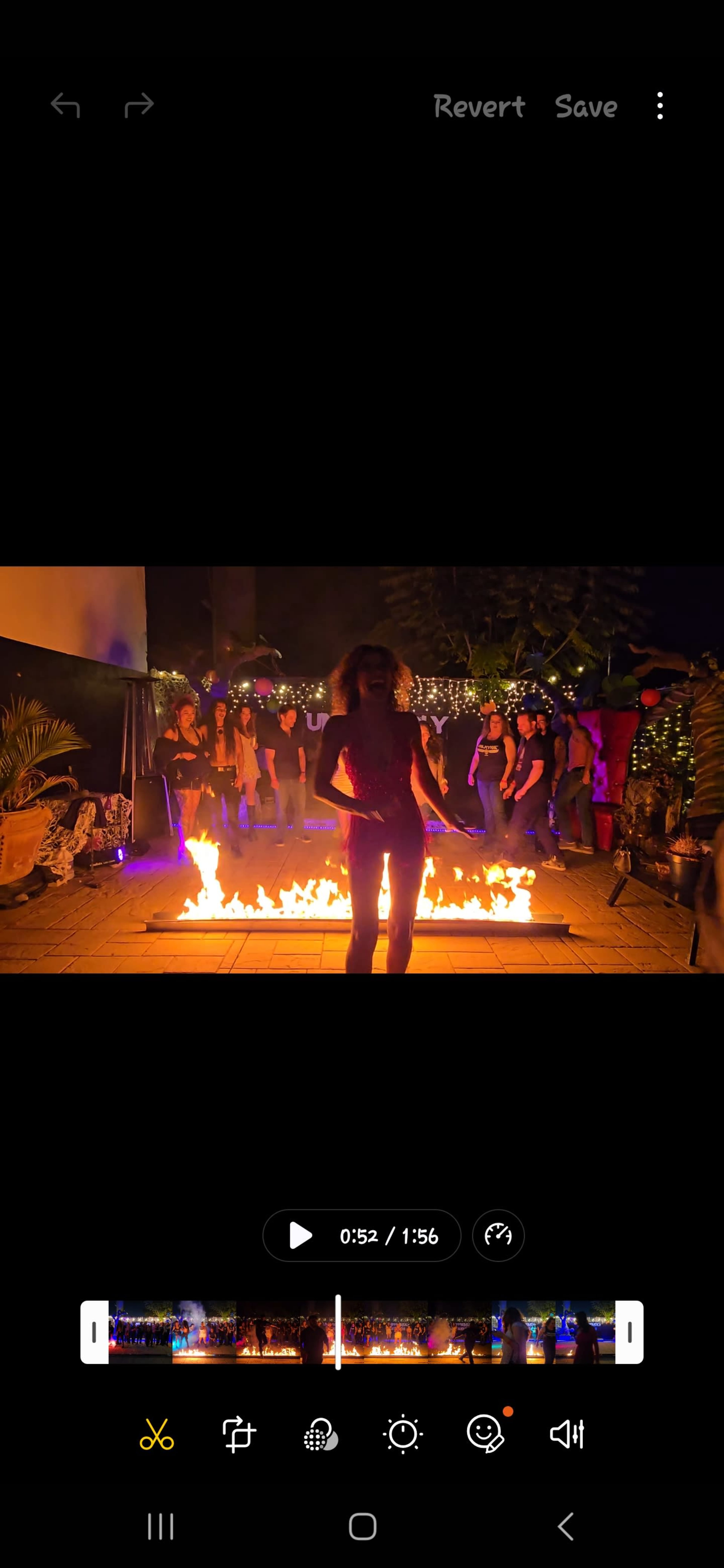 A person is standing in front of a fire performance, surrounded by onlookers in a festive setting at night.