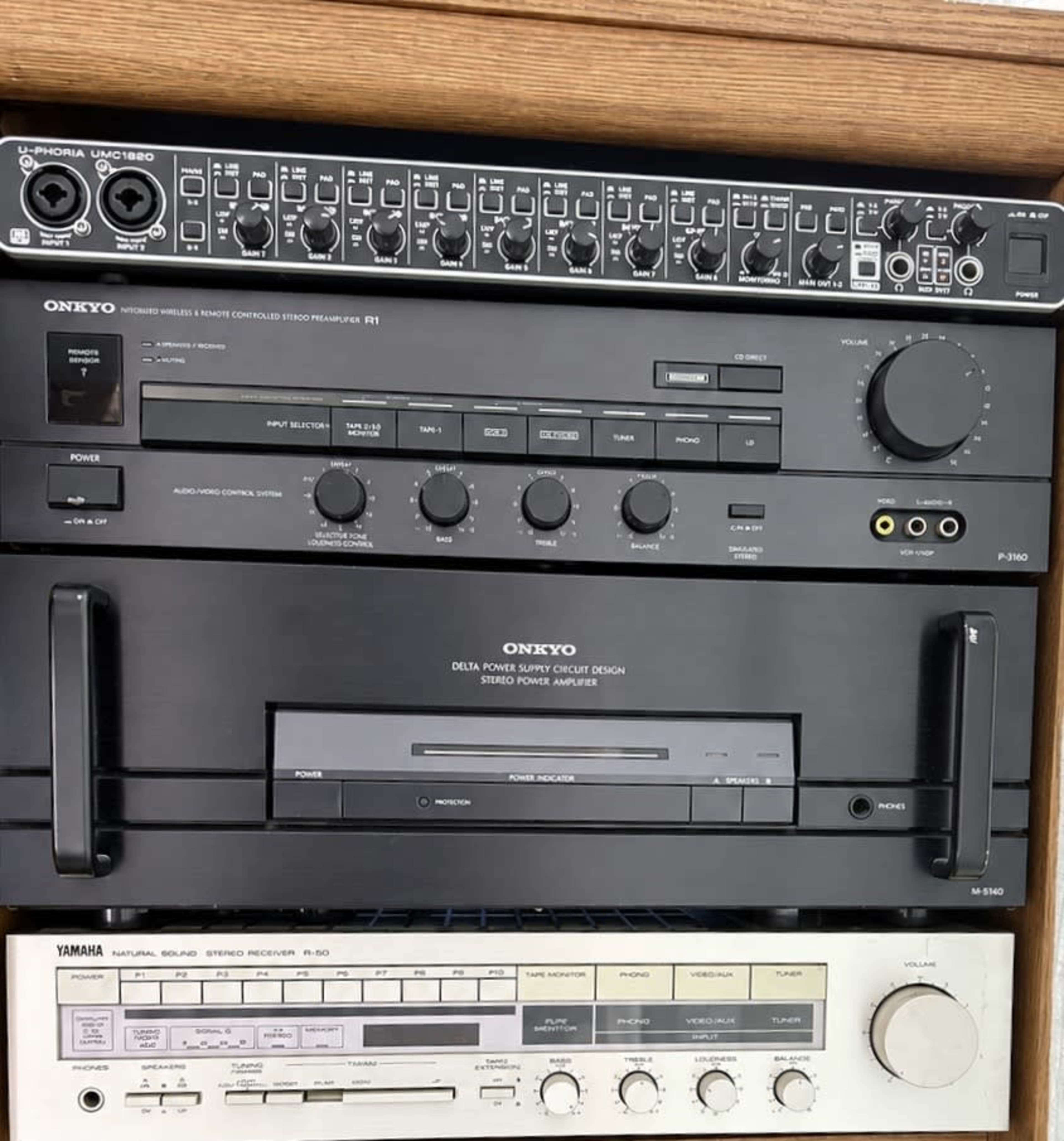 The image shows a stack of audio equipment, including an Onkyo receiver, a CD player, and a Yamaha audio recorder housed in a wooden cabinet.