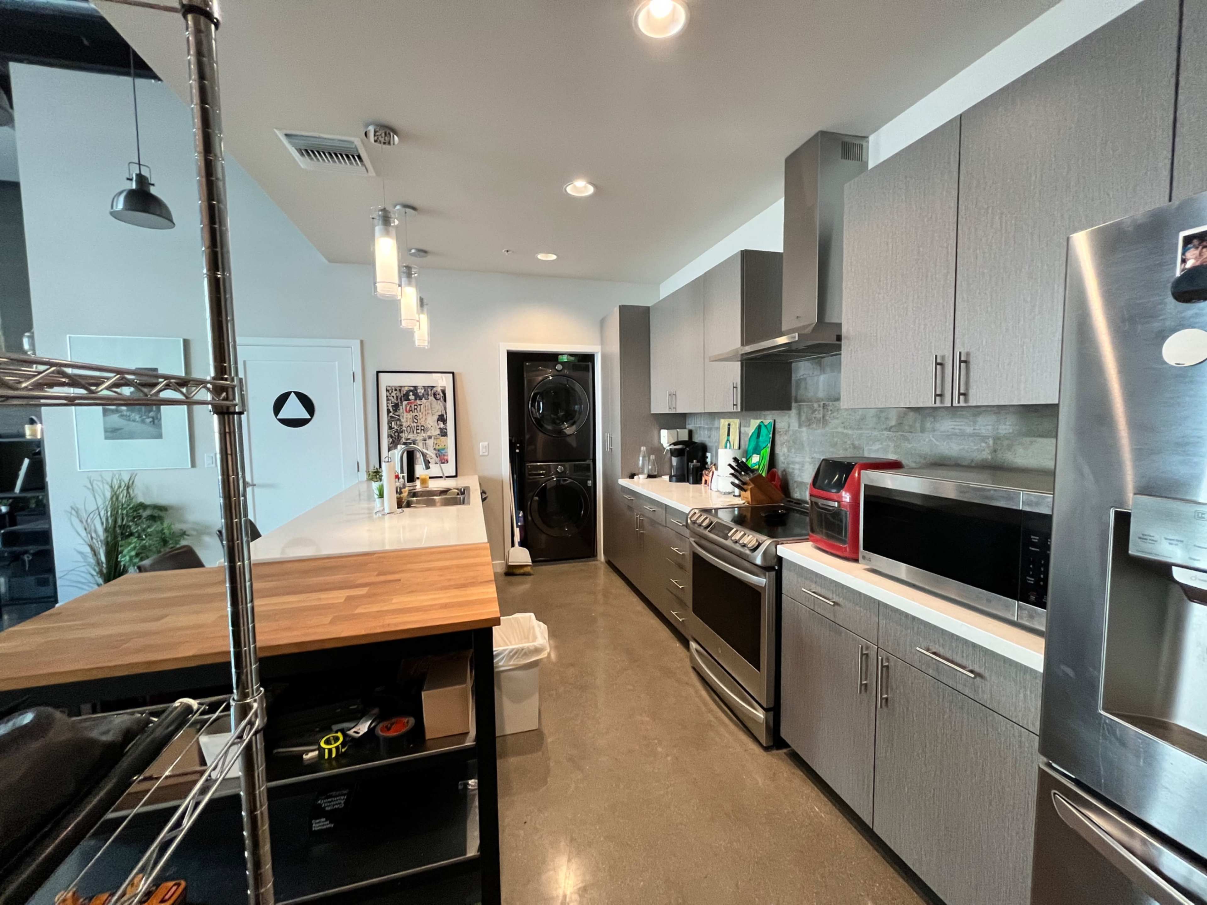A modern kitchen with stainless steel appliances, gray cabinetry, and a central island with a wooden countertop.