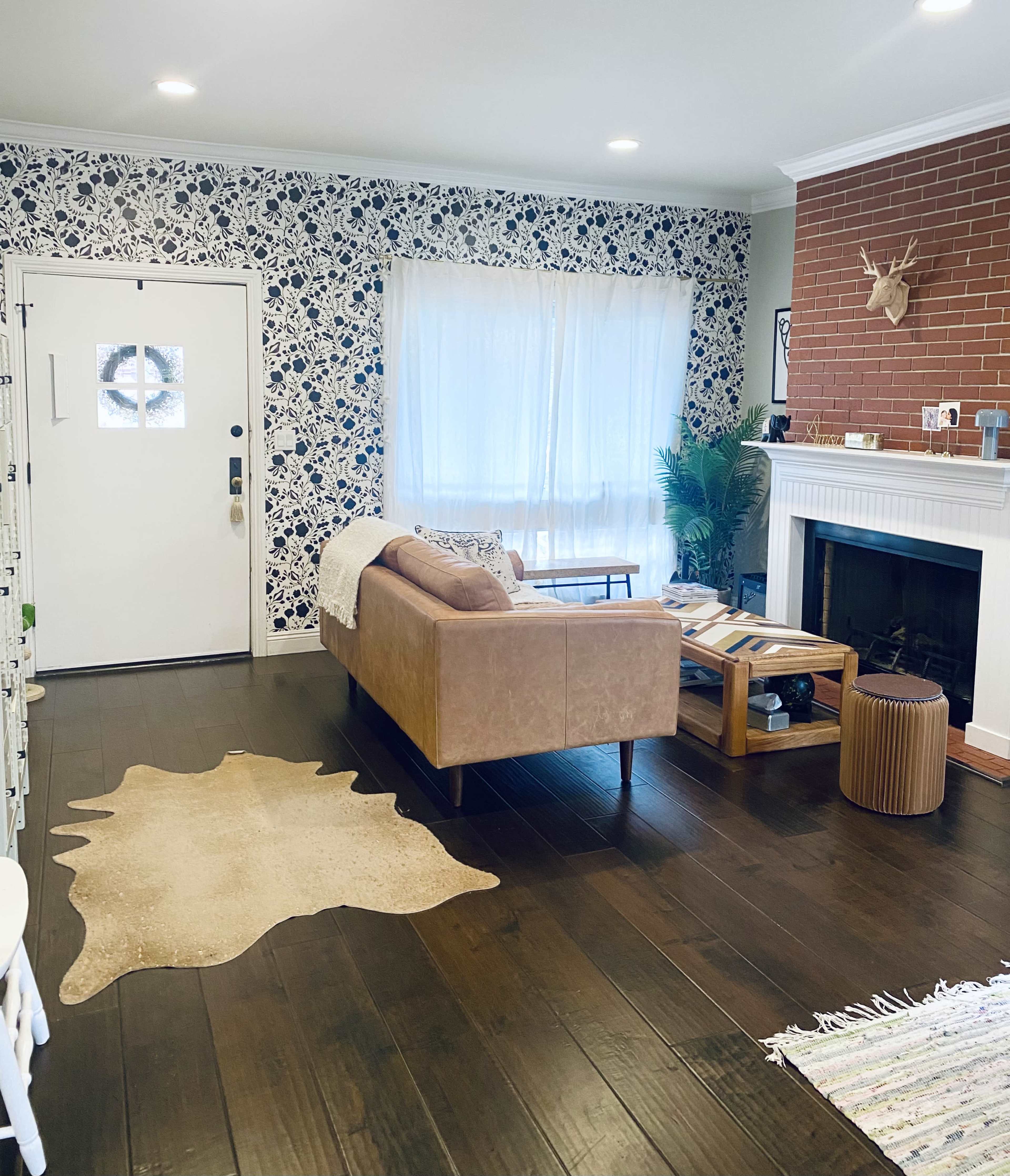 The living room features a sectional sofa, a coffee table, a decorative rug, and a fireplace against a patterned wall.