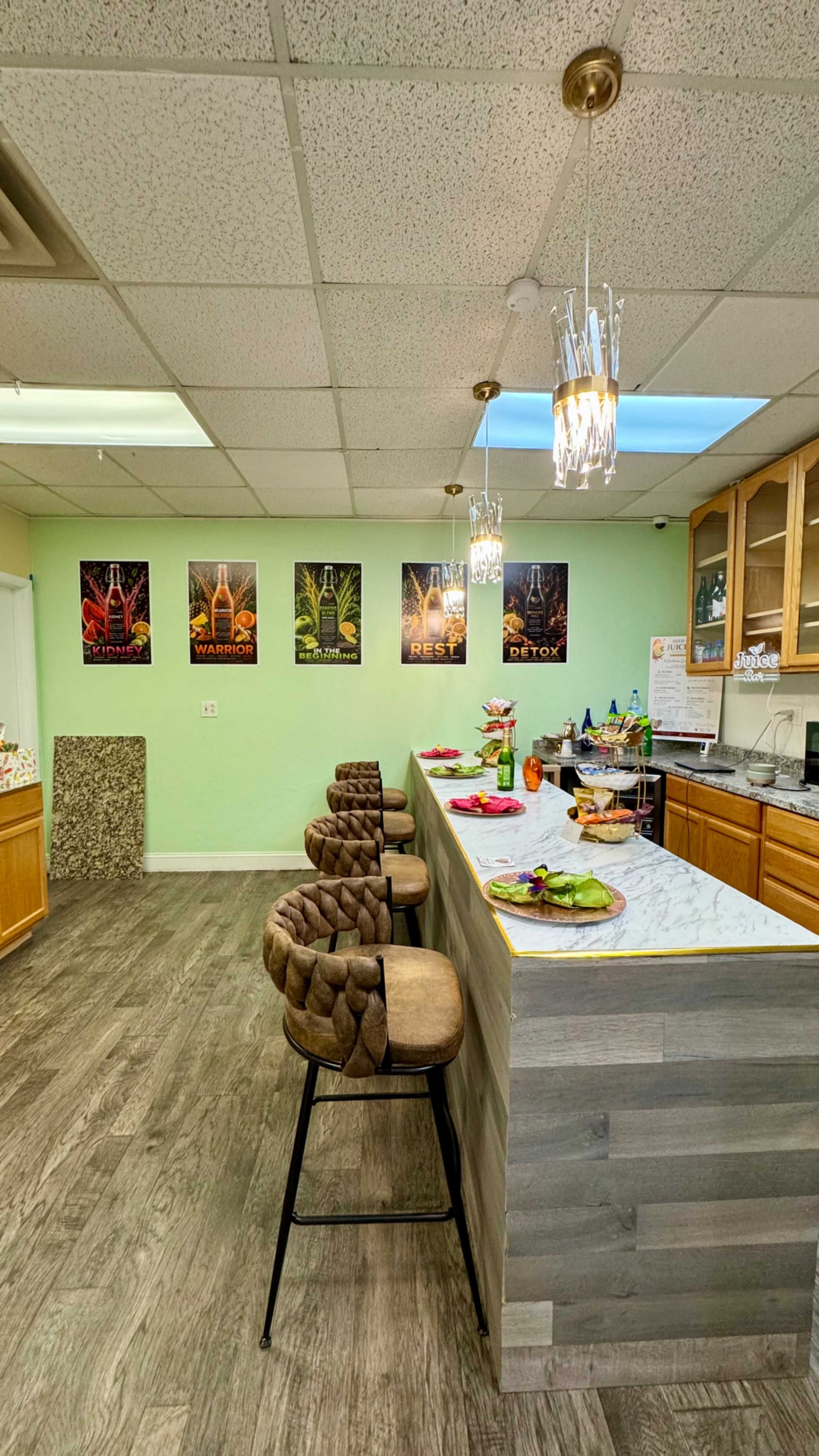 The image shows a kitchen area with a marble counter, bar stools, and posters on the wall featuring colorful designs.