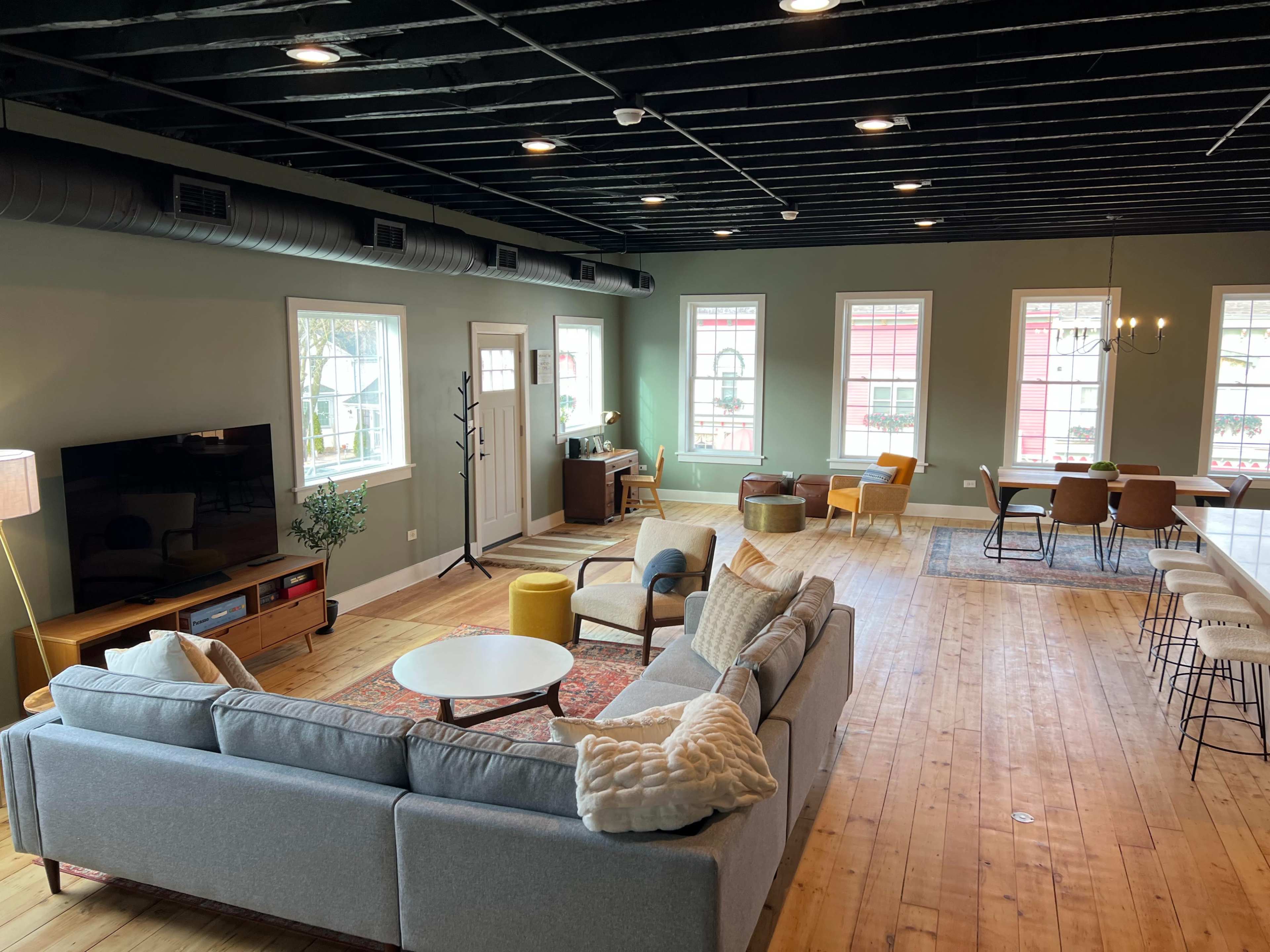 A spacious living area with a sectional sofa, television, dining space, and large windows that let in natural light.