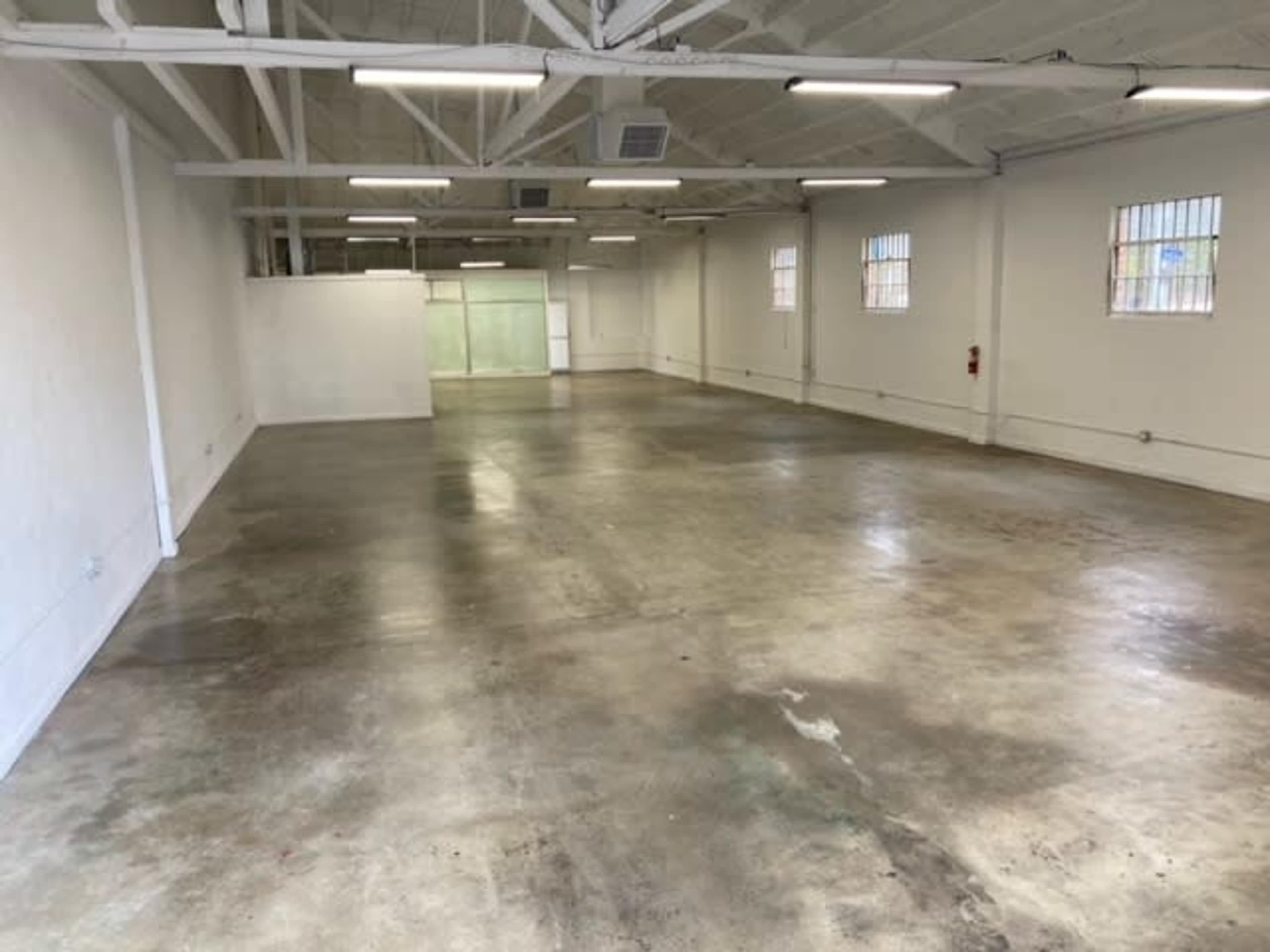A spacious, empty warehouse with concrete floors and white walls.