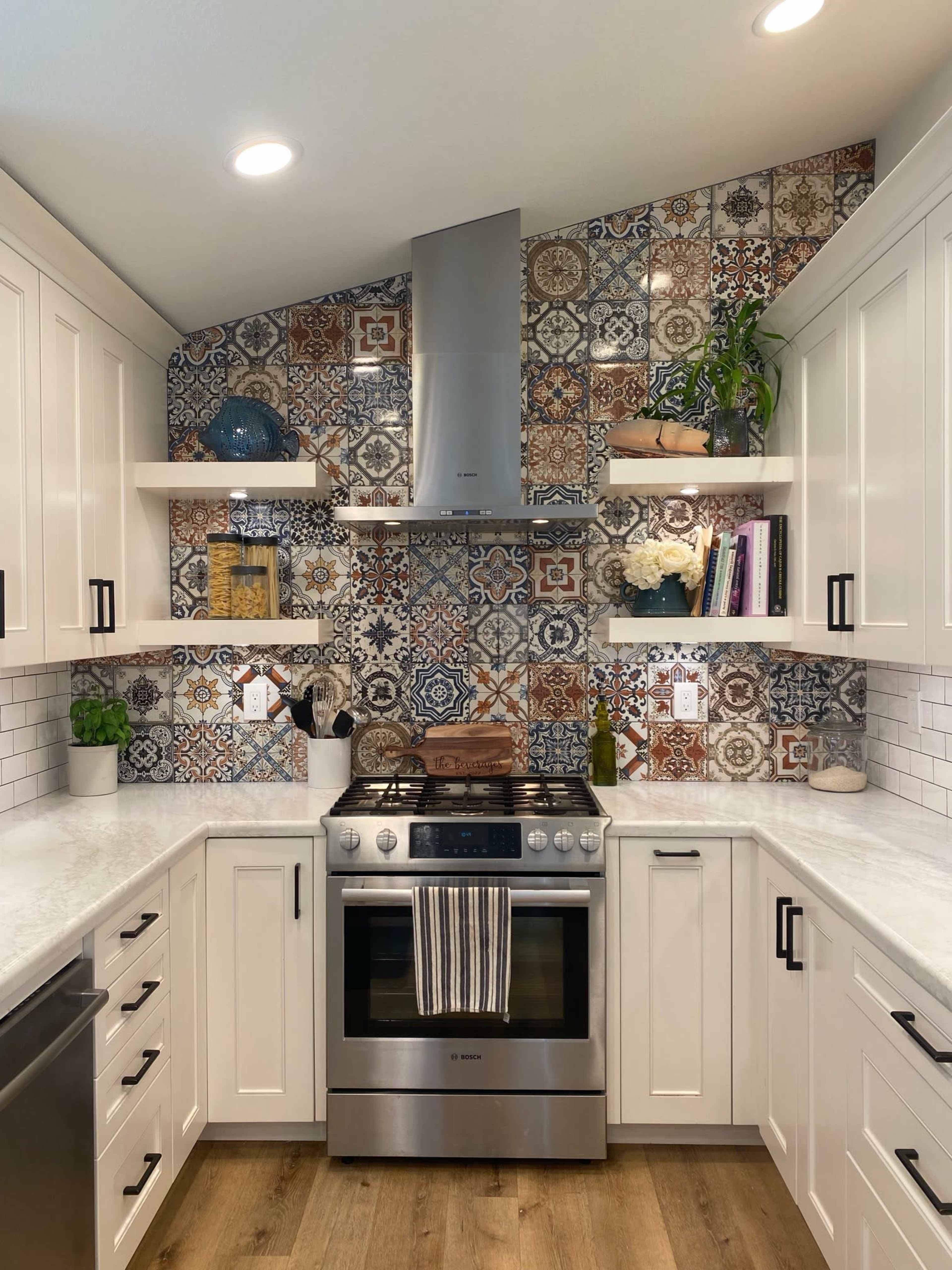 A modern kitchen features a patterned tile backsplash, white cabinets, stainless steel appliances, and wooden flooring.