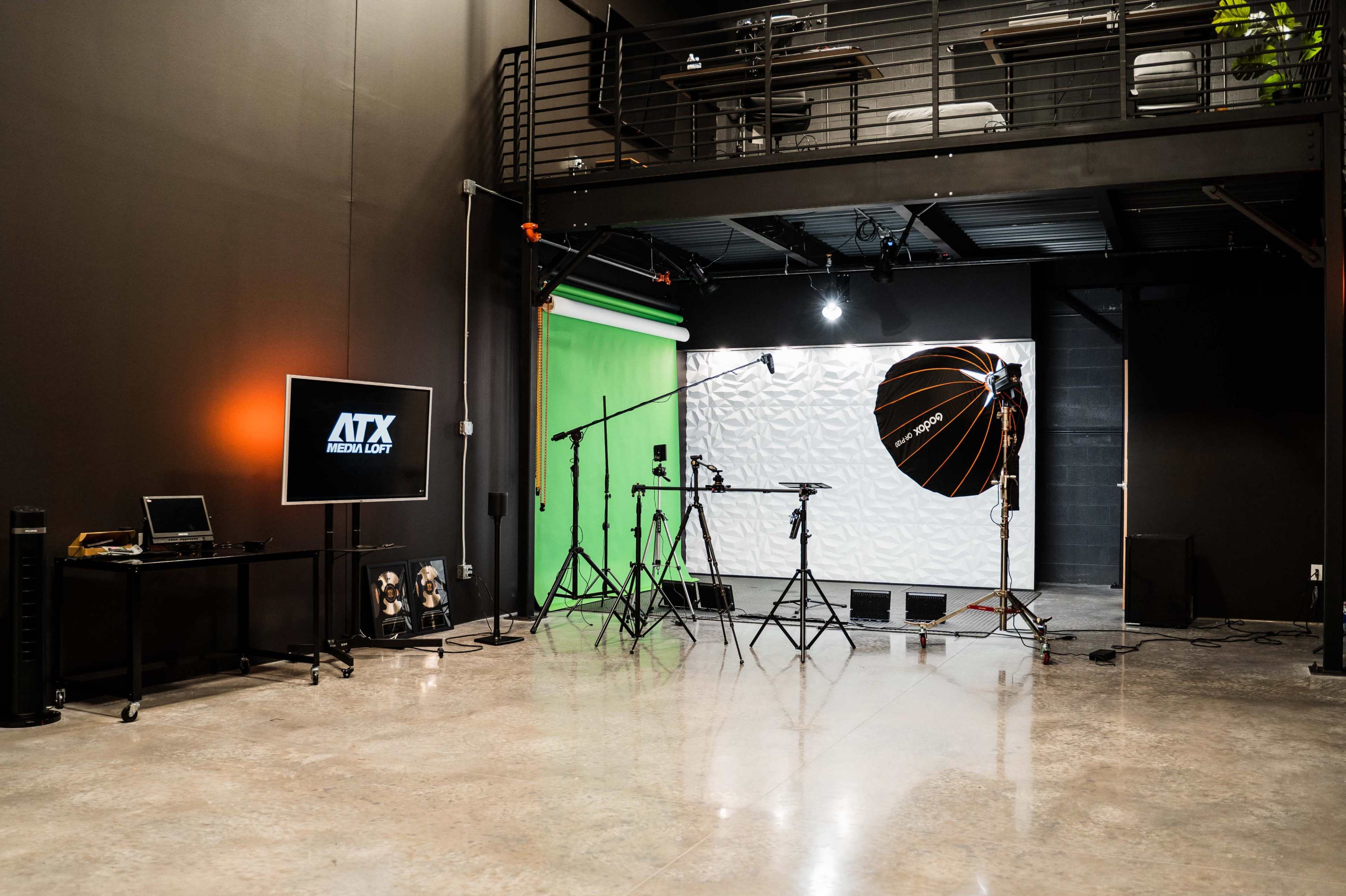 The image shows a photography studio with a green screen, lighting equipment, and a television monitor displaying a logo.