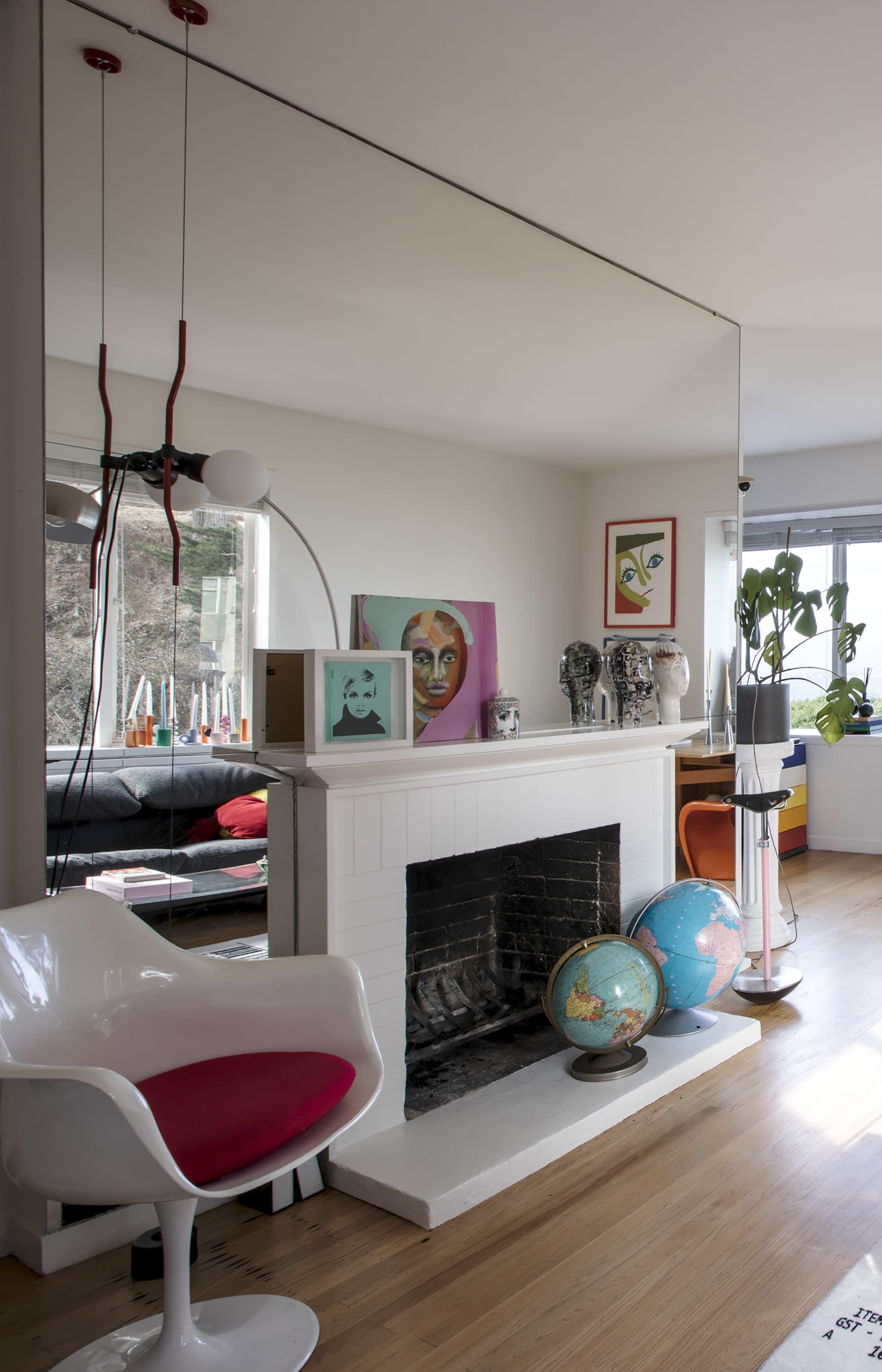The image features a modern living room with a white fireplace, colorful artwork, decorative globes, and a stylish chair in the foreground.