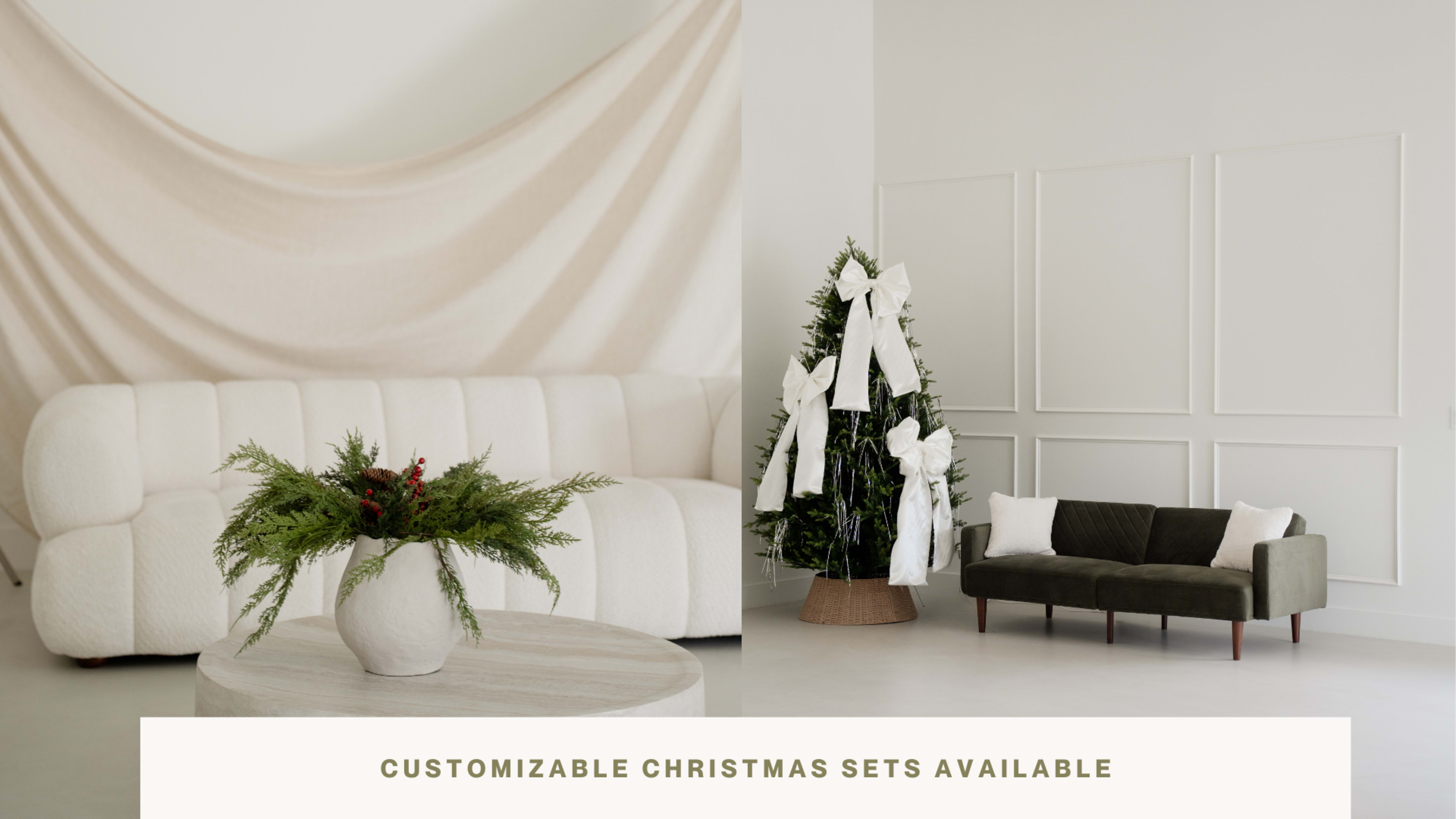 The image features a modern living space with a white couch, a round coffee table with greenery, and a decorated Christmas tree next to a dark green sofa.