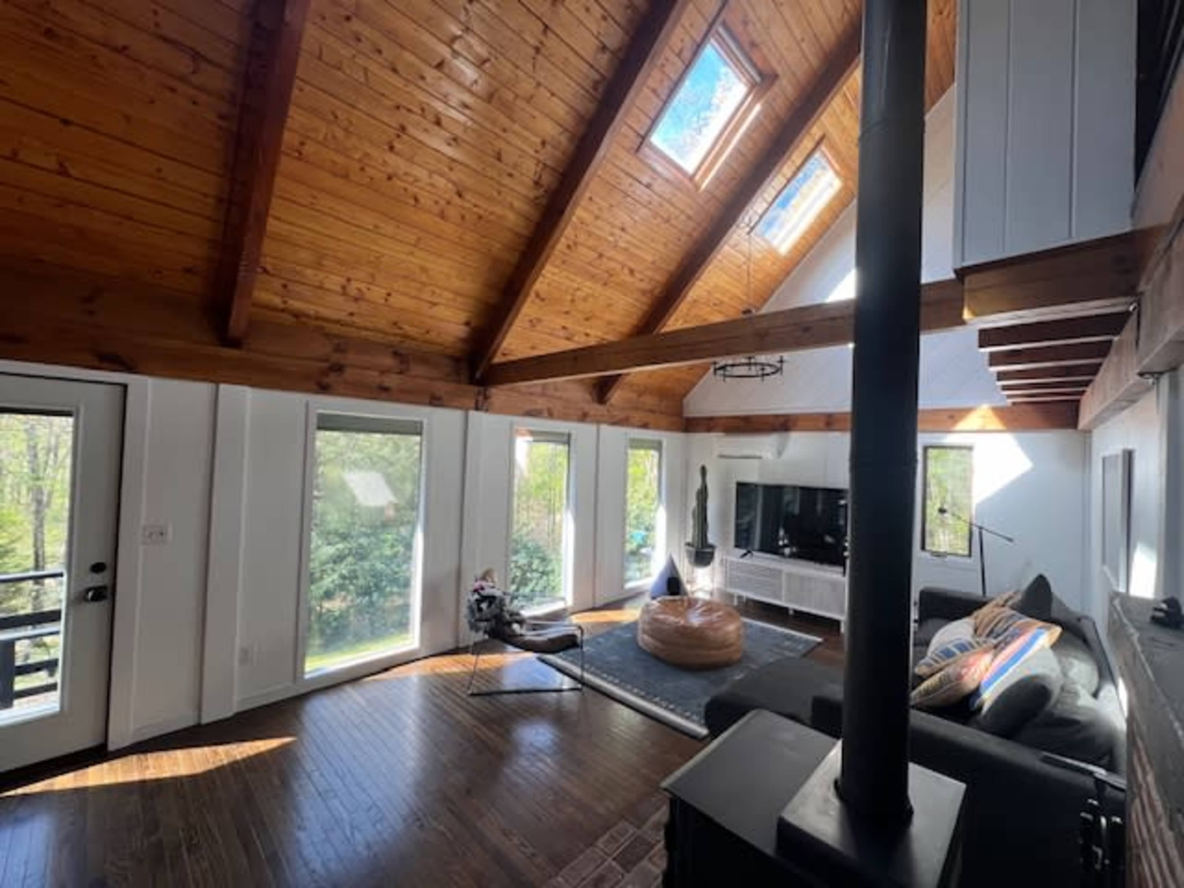 A bright, airy living room with vaulted wooden ceilings, large windows, and modern furnishings.