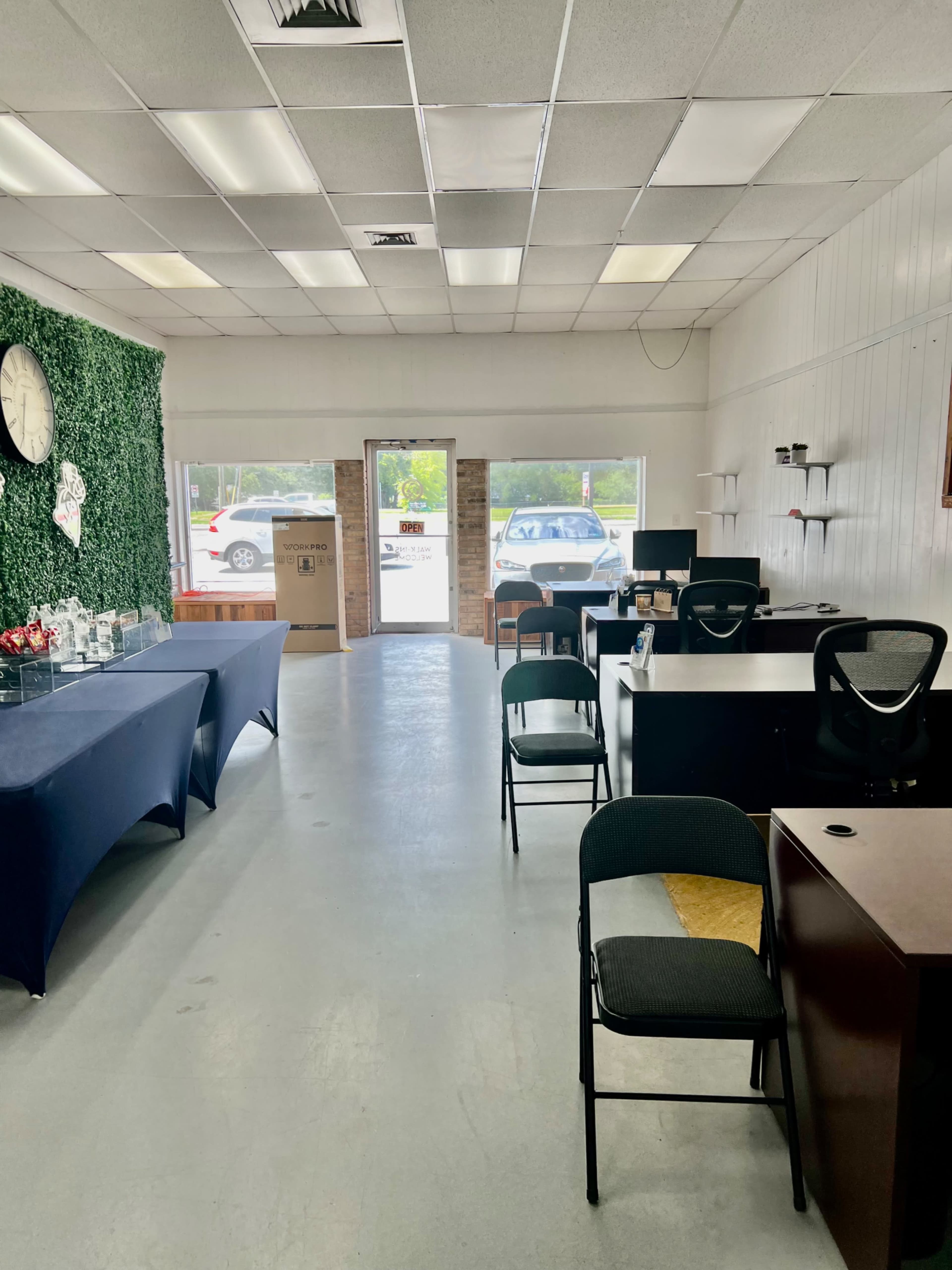 A clean, empty interior of a commercial space with tables, chairs, and a large window facing the parking lot.