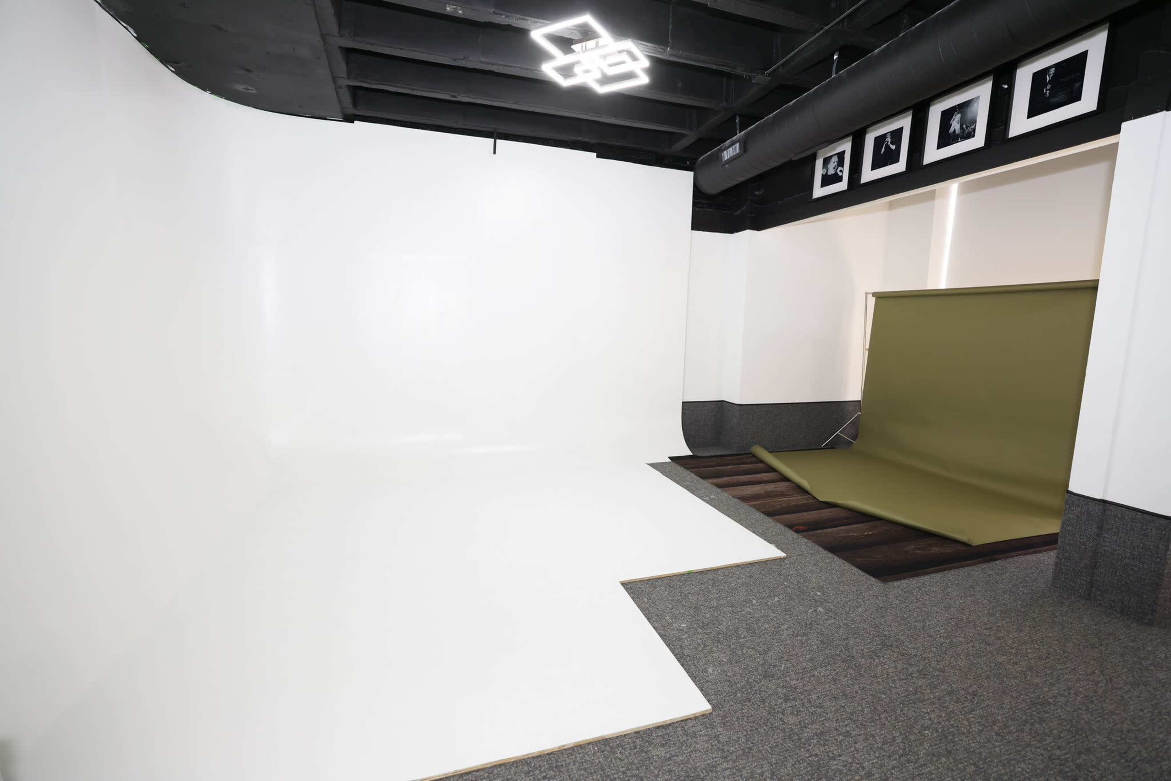 A photography studio with a white backdrop on the left and an olive green backdrop folded on the right.