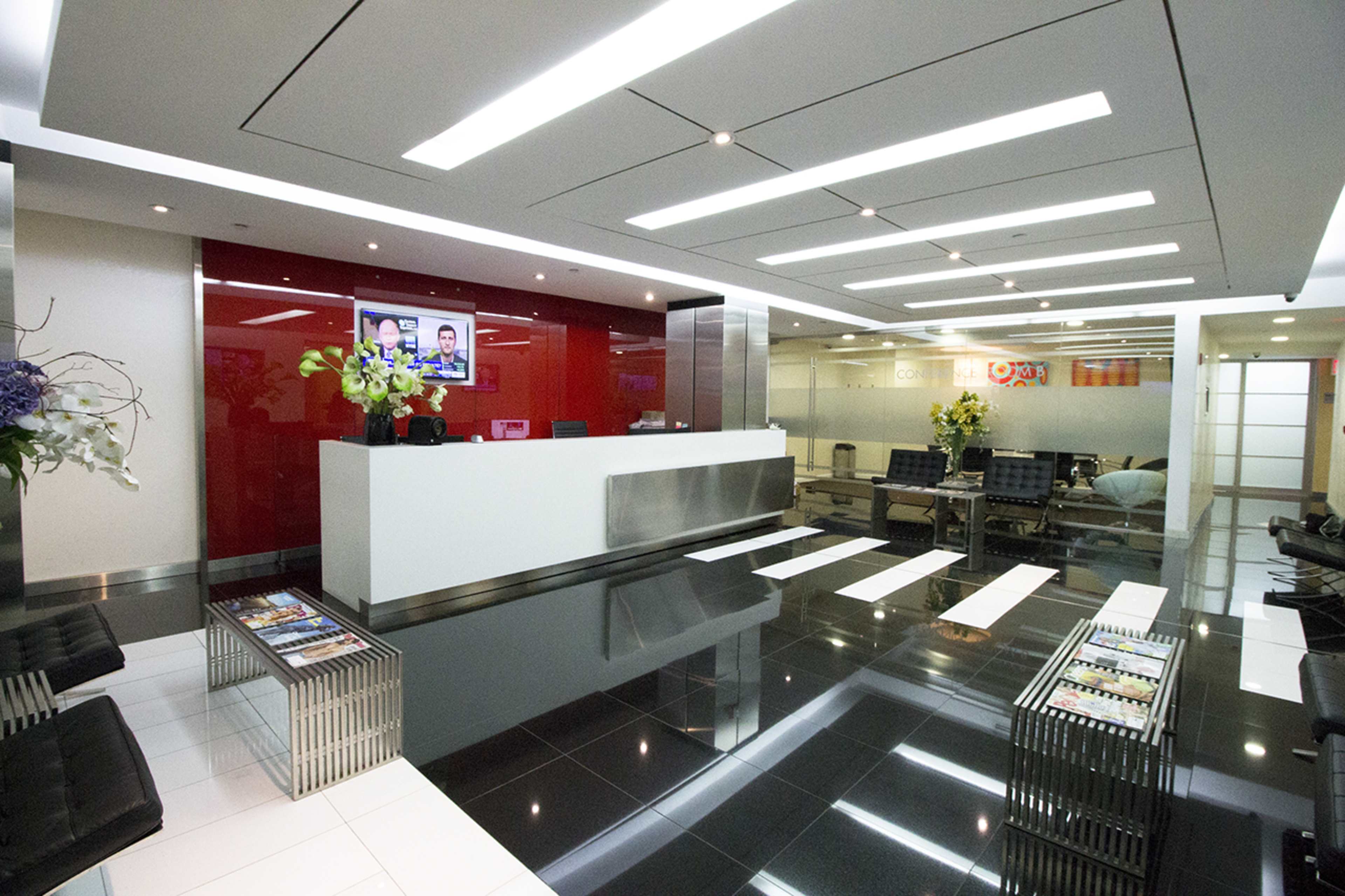 A modern reception area with a glossy black and white tiled floor, a sleek front desk, and seating arrangements, complemented by decorative plants and a television display.