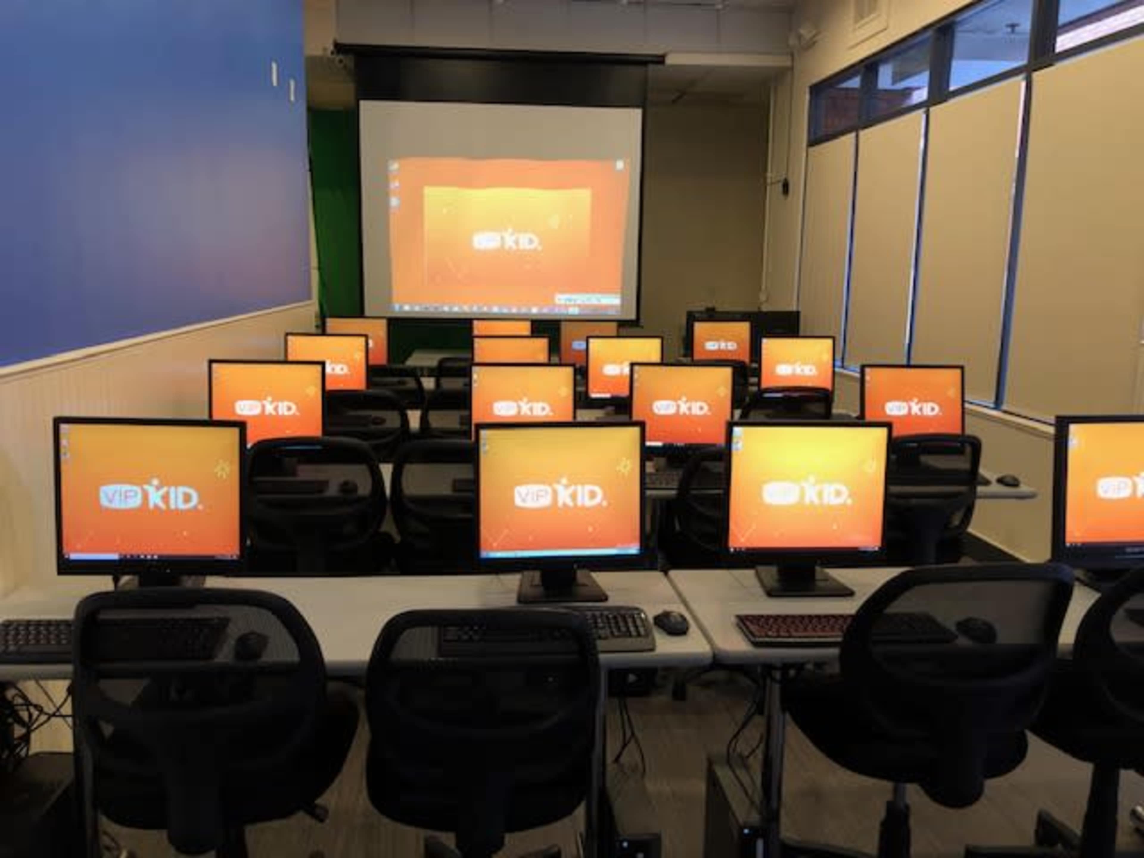 A classroom filled with multiple computer stations, each displaying the VIPKID logo on the screens.