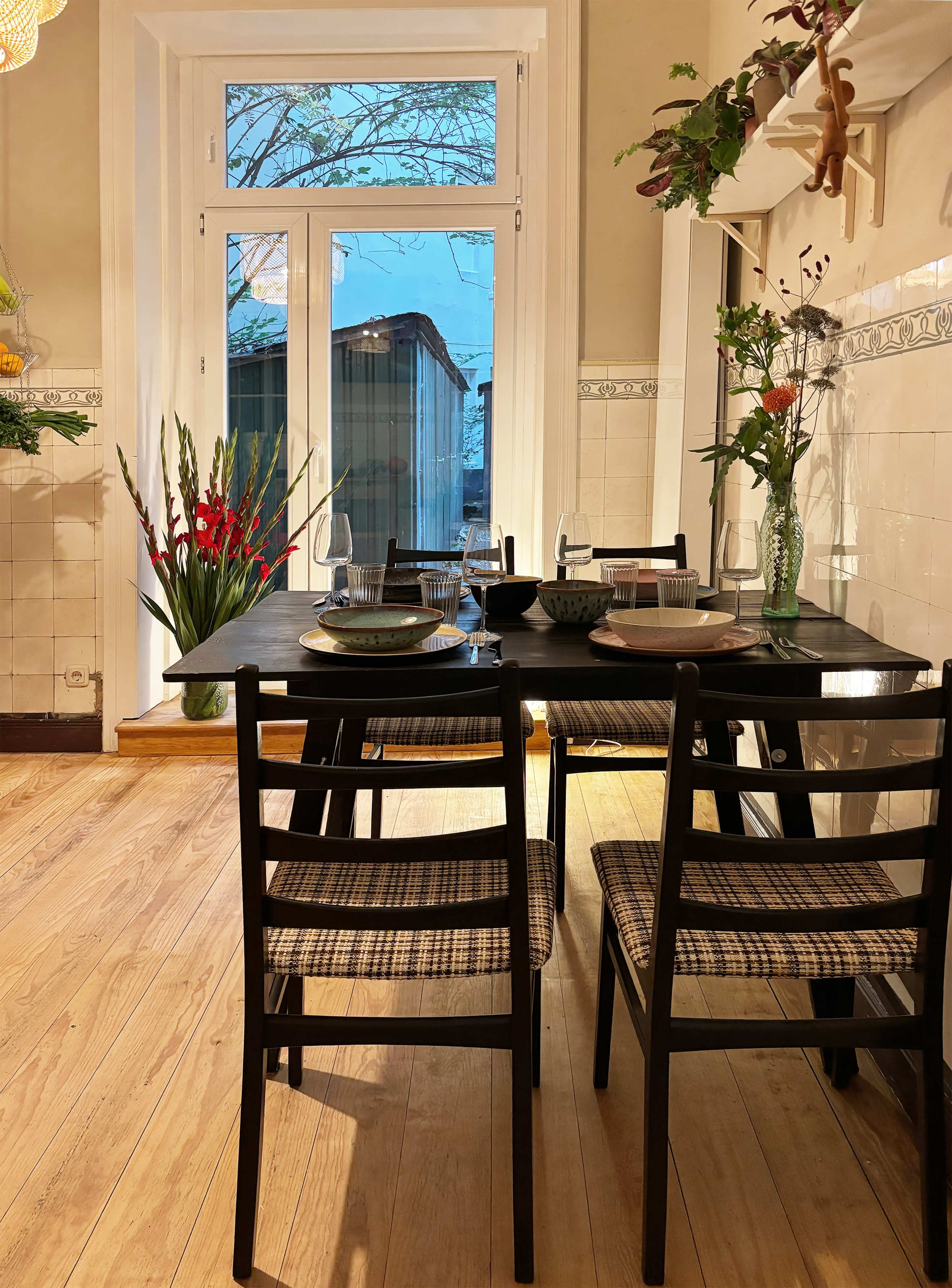 A dining table set for a meal is positioned next to a window, showcasing bare trees outside.