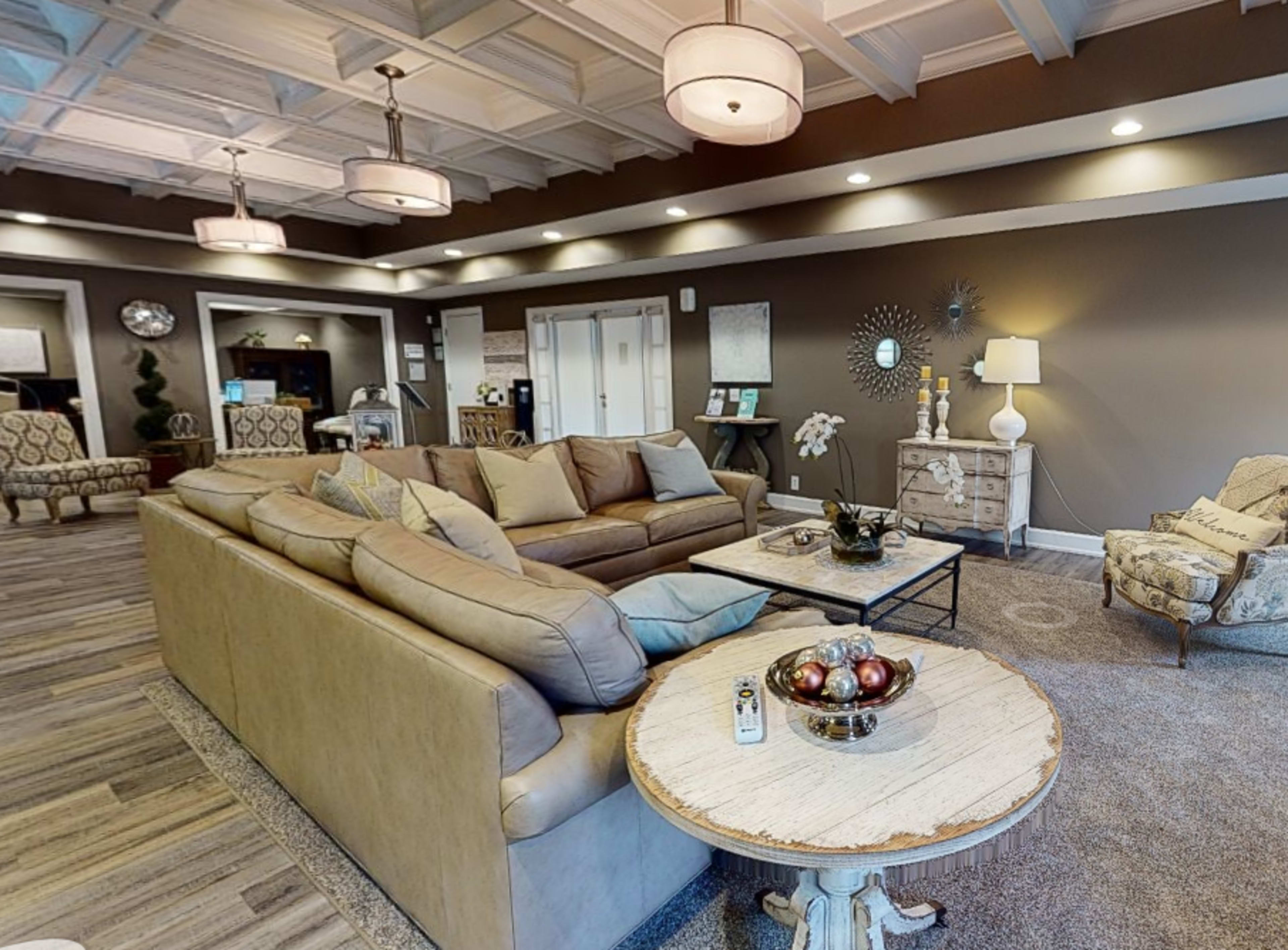 A spacious lounge area with beige sofas, a round table with decorative items, and elegant light fixtures.