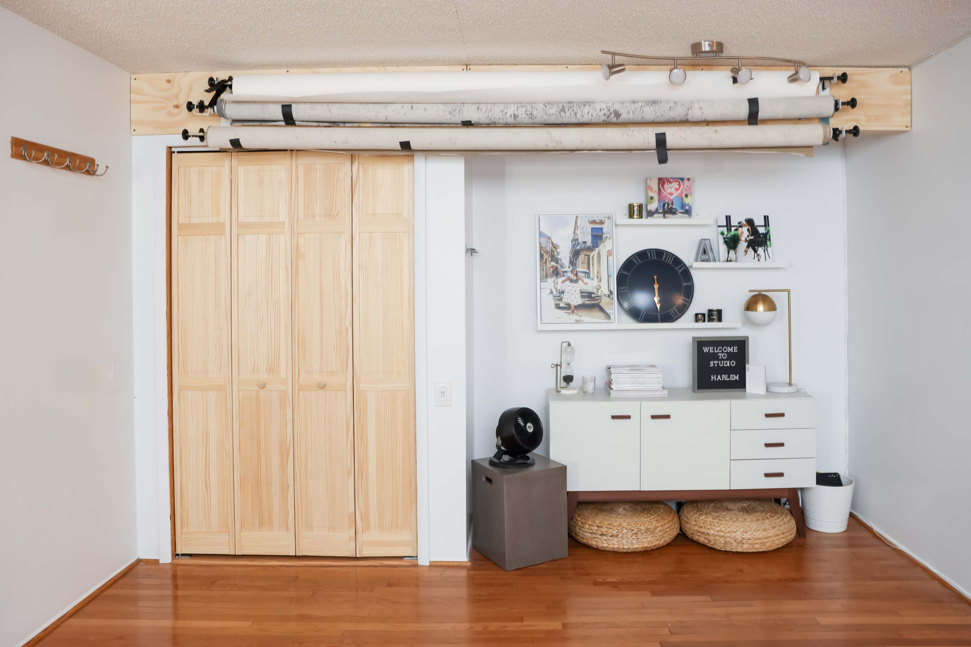 A minimalist interior space features a wooden closet, a low cabinet with decor, and ski equipment mounted on the wall.