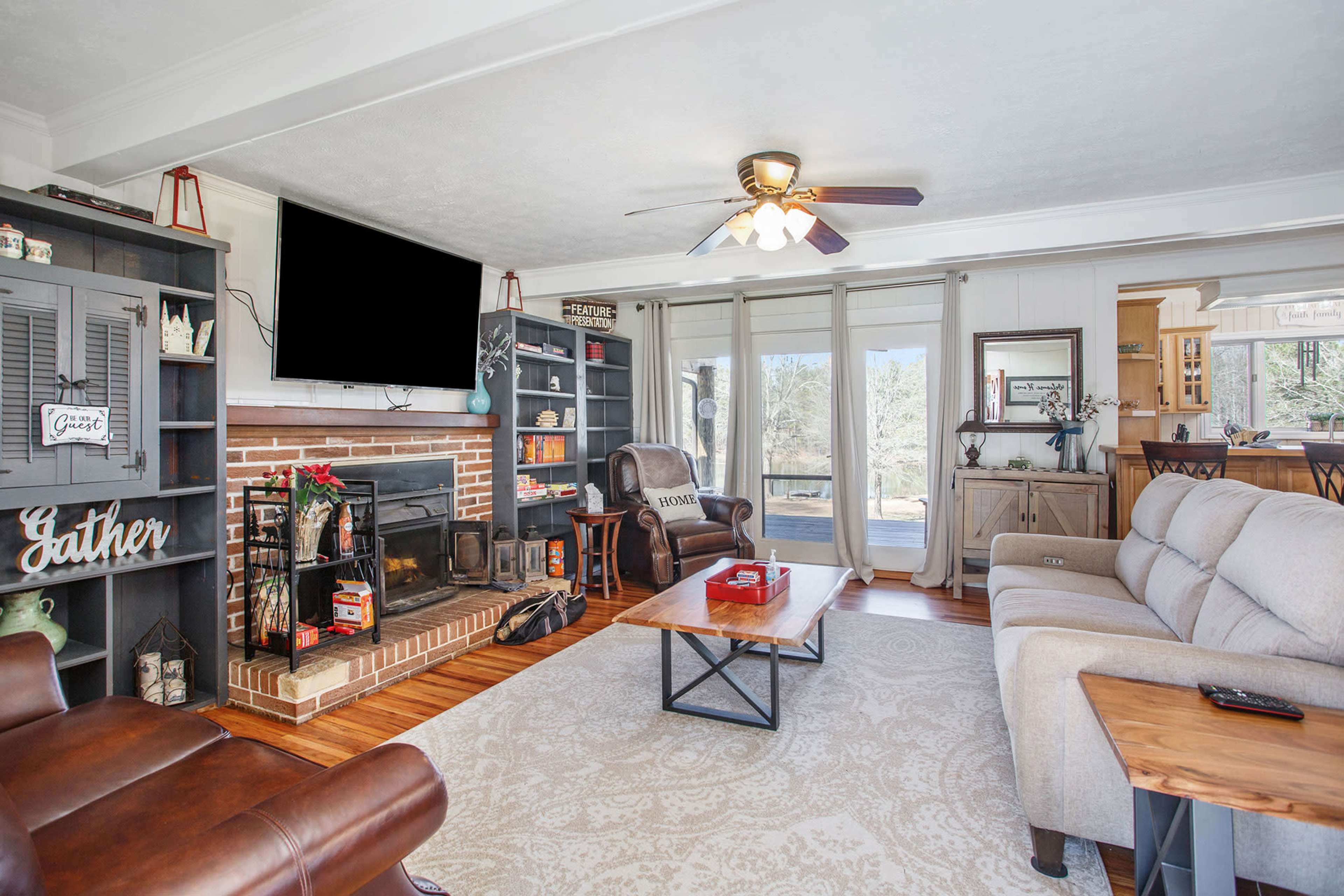 A cozy living room features a fireplace, comfortable seating, and a large window with natural light.