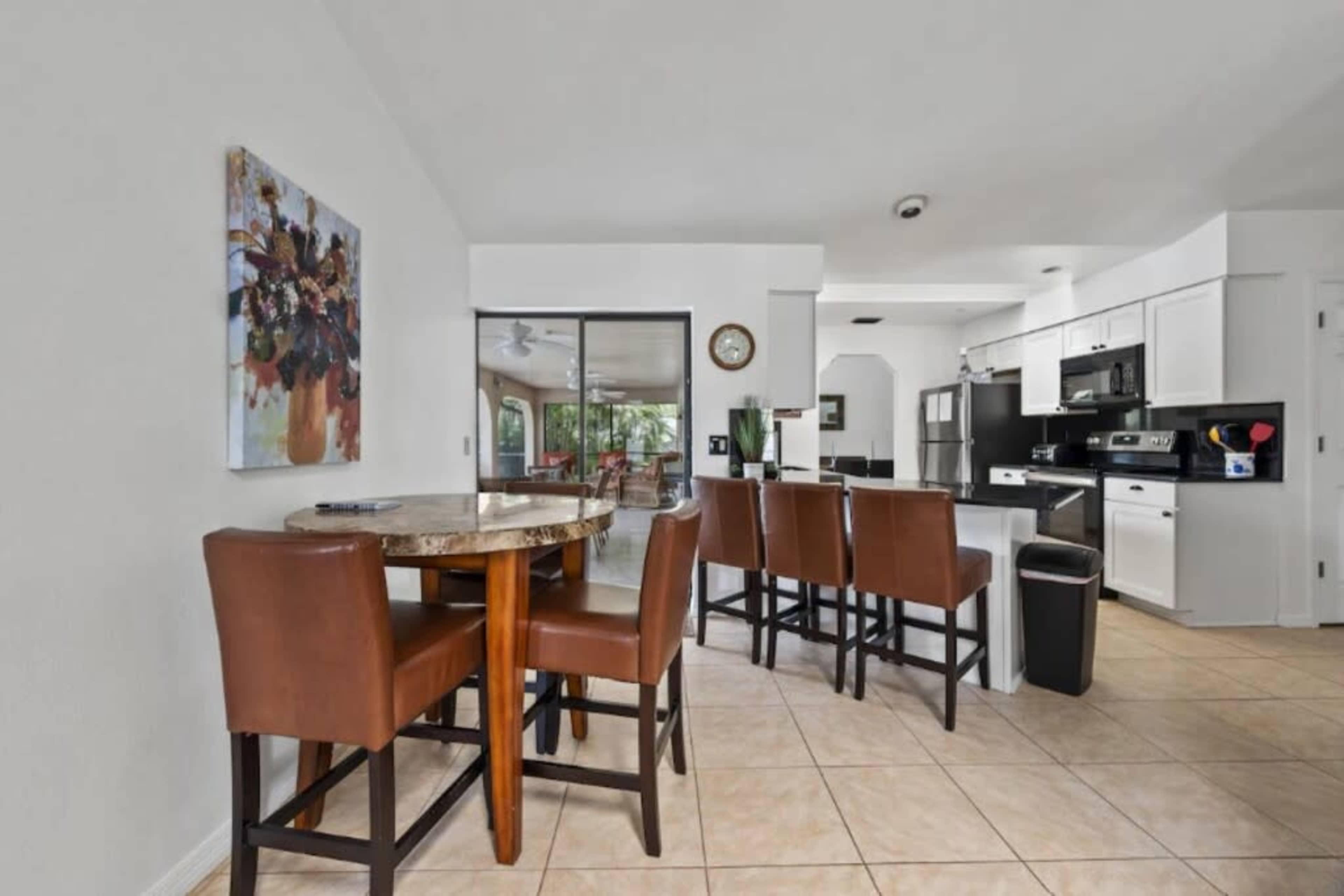 A modern kitchen and dining area features a round table with four brown chairs, an open layout, and access to a glass sliding door leading to an outside space.