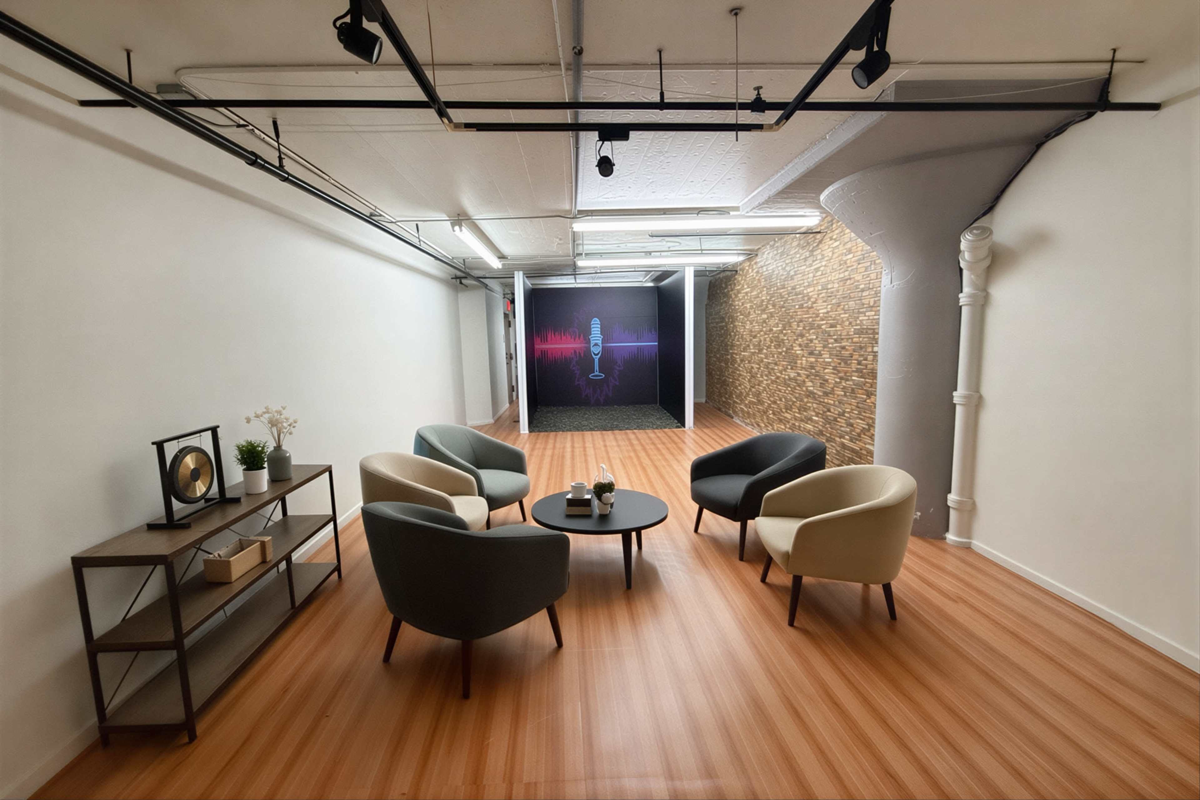 The image shows a modern, minimalist room with four armchairs arranged around a circular table, and a backdrop featuring a microphone design against a textured wall.
