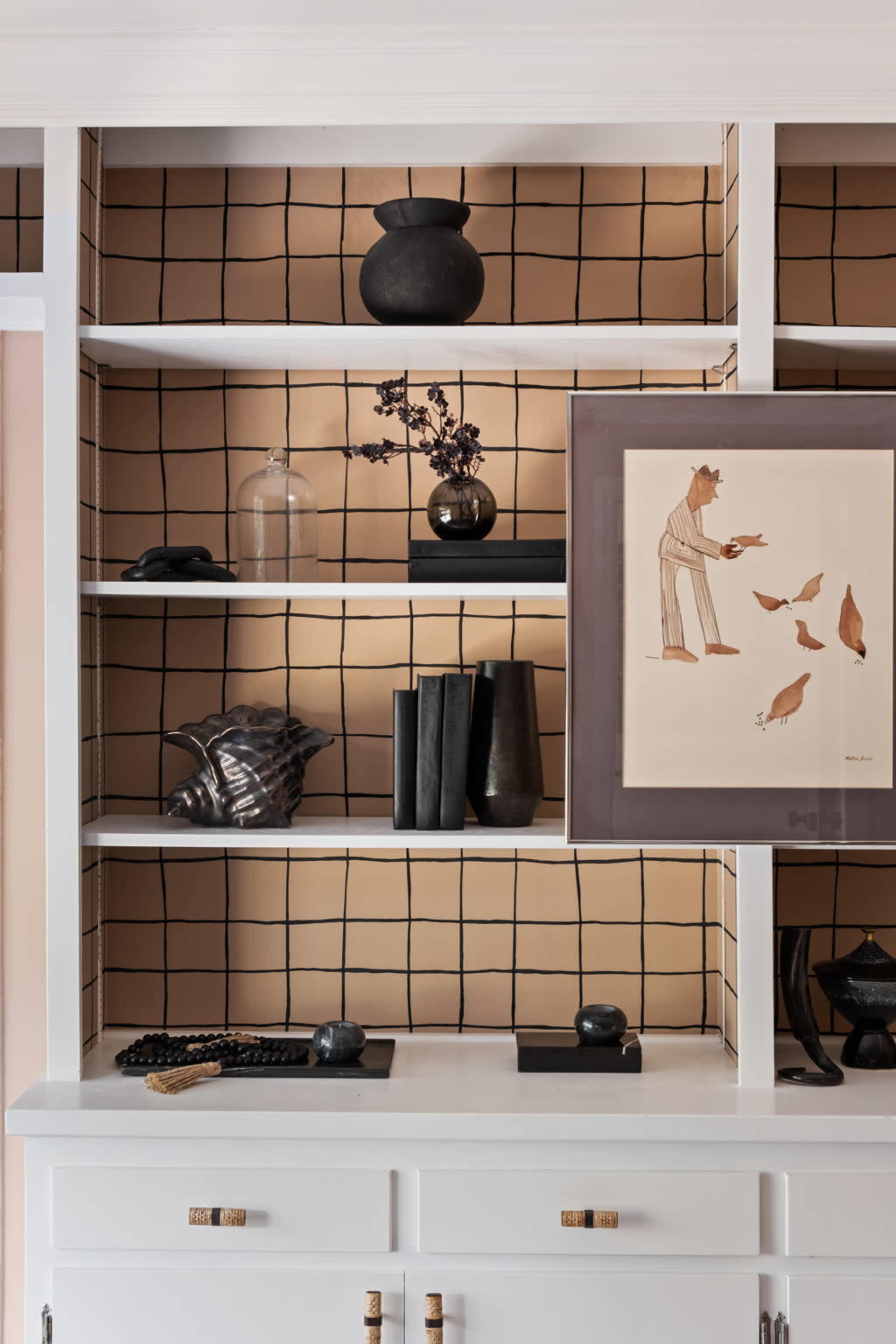A modern shelving unit displays a variety of decorative items, including vases, books, and artwork, against a grid-patterned background.