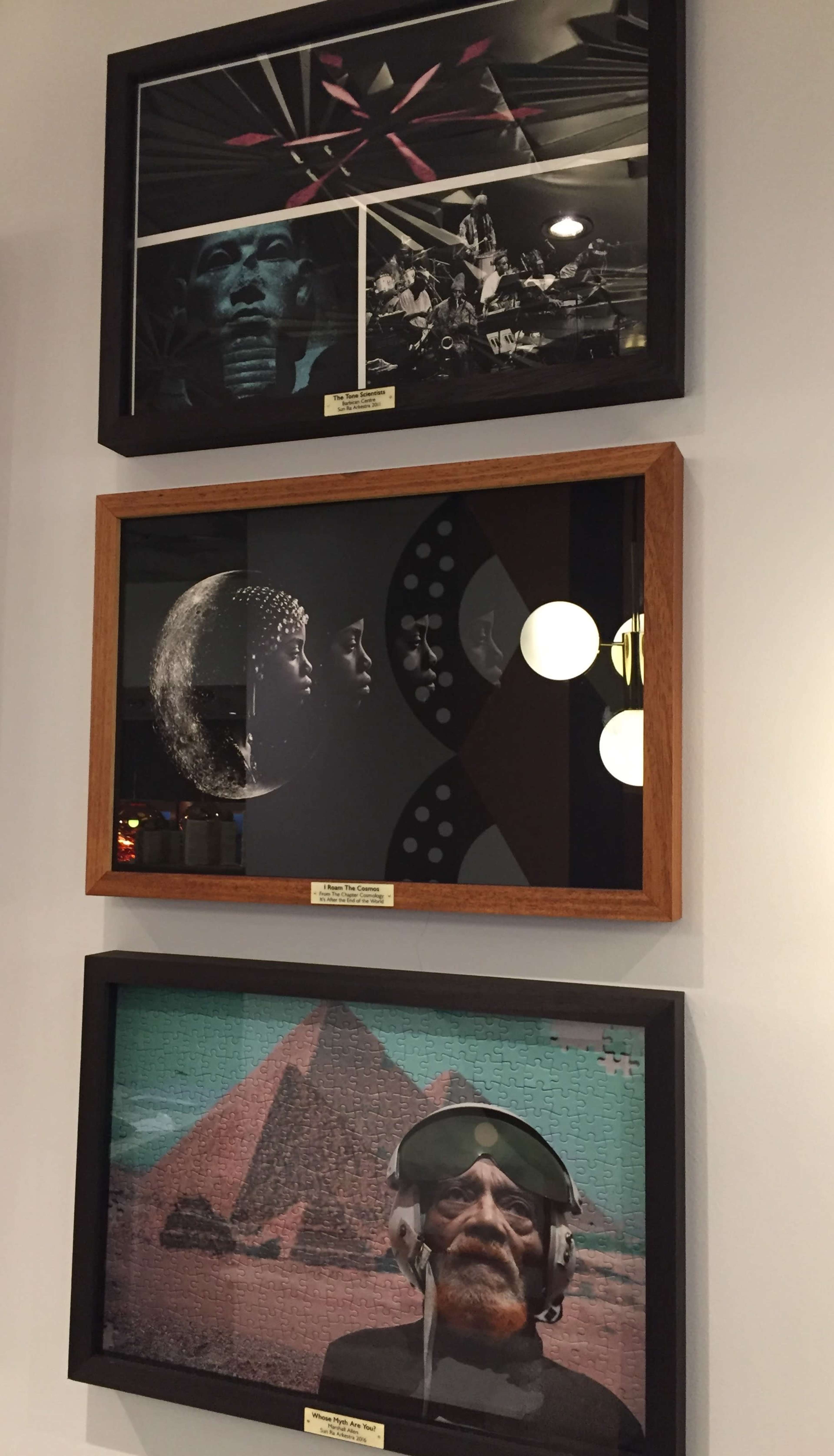 Three framed artistic panels arranged vertically on a wall, featuring abstract and thematic visuals including a musician, cosmic elements, and pyramids.