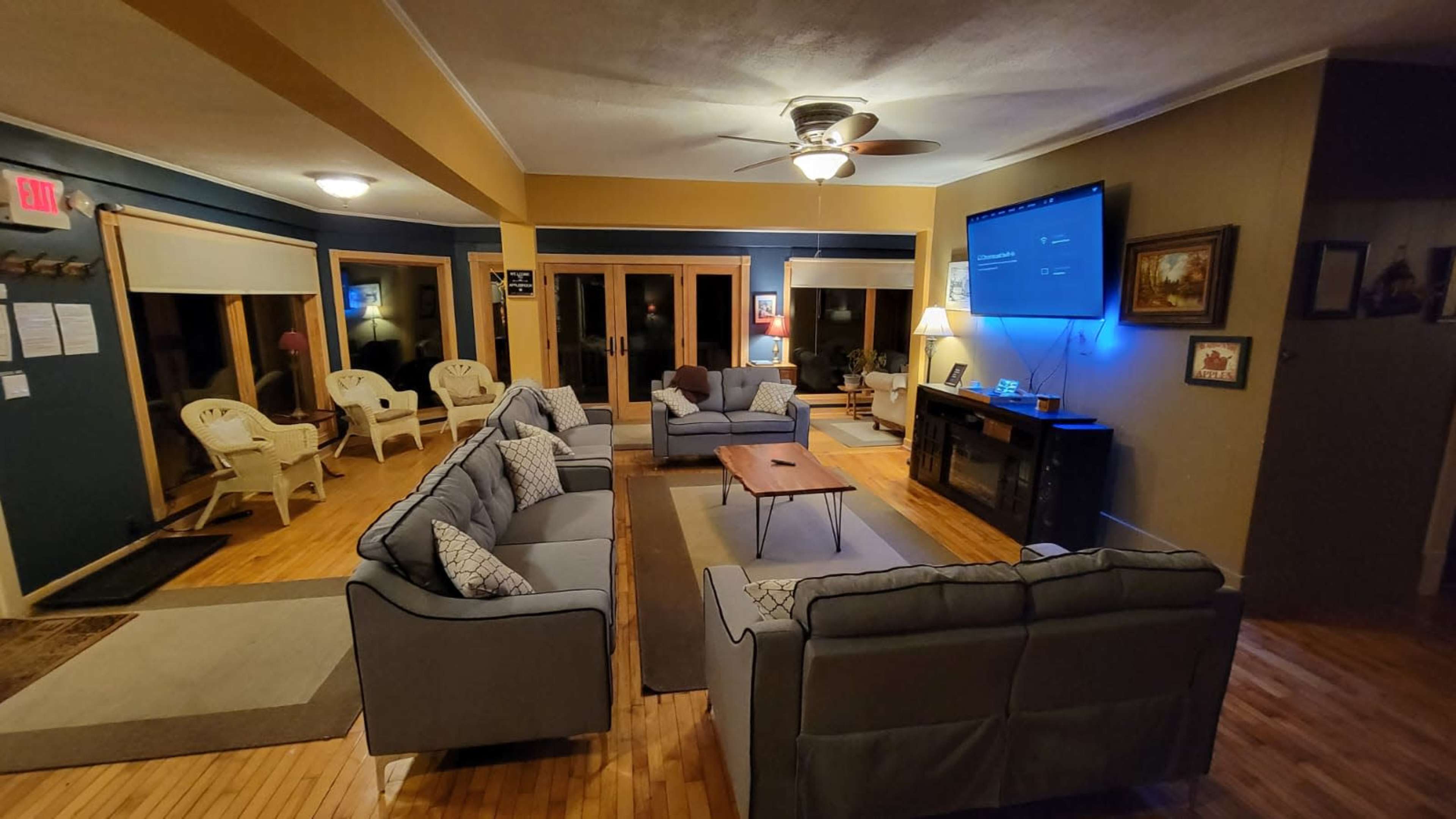 A spacious living room features a seating arrangement with gray sofas, a central coffee table, and a large wall-mounted TV.