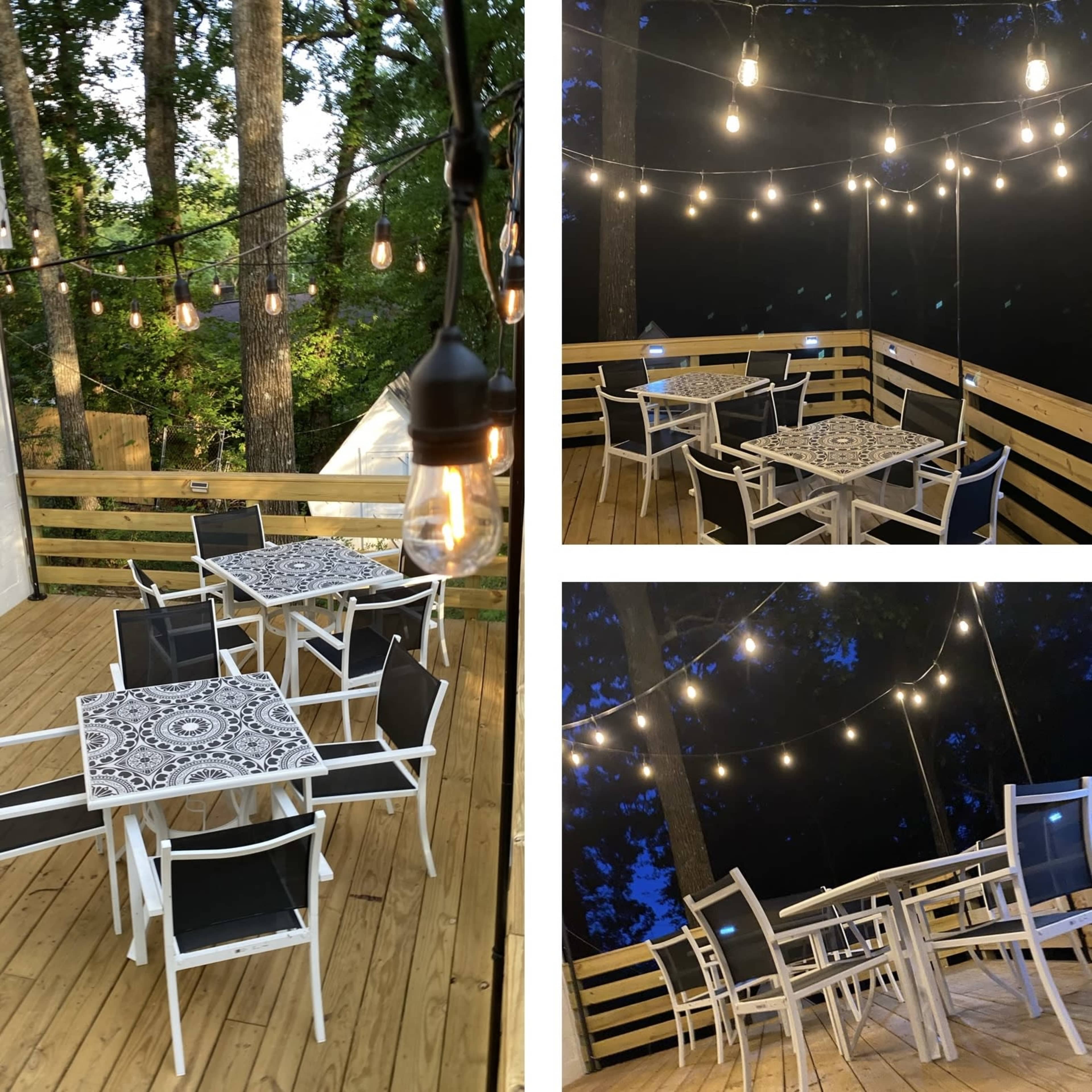 An outdoor deck area with wooden flooring, decorated with string lights and furnished with white tables and black chairs.