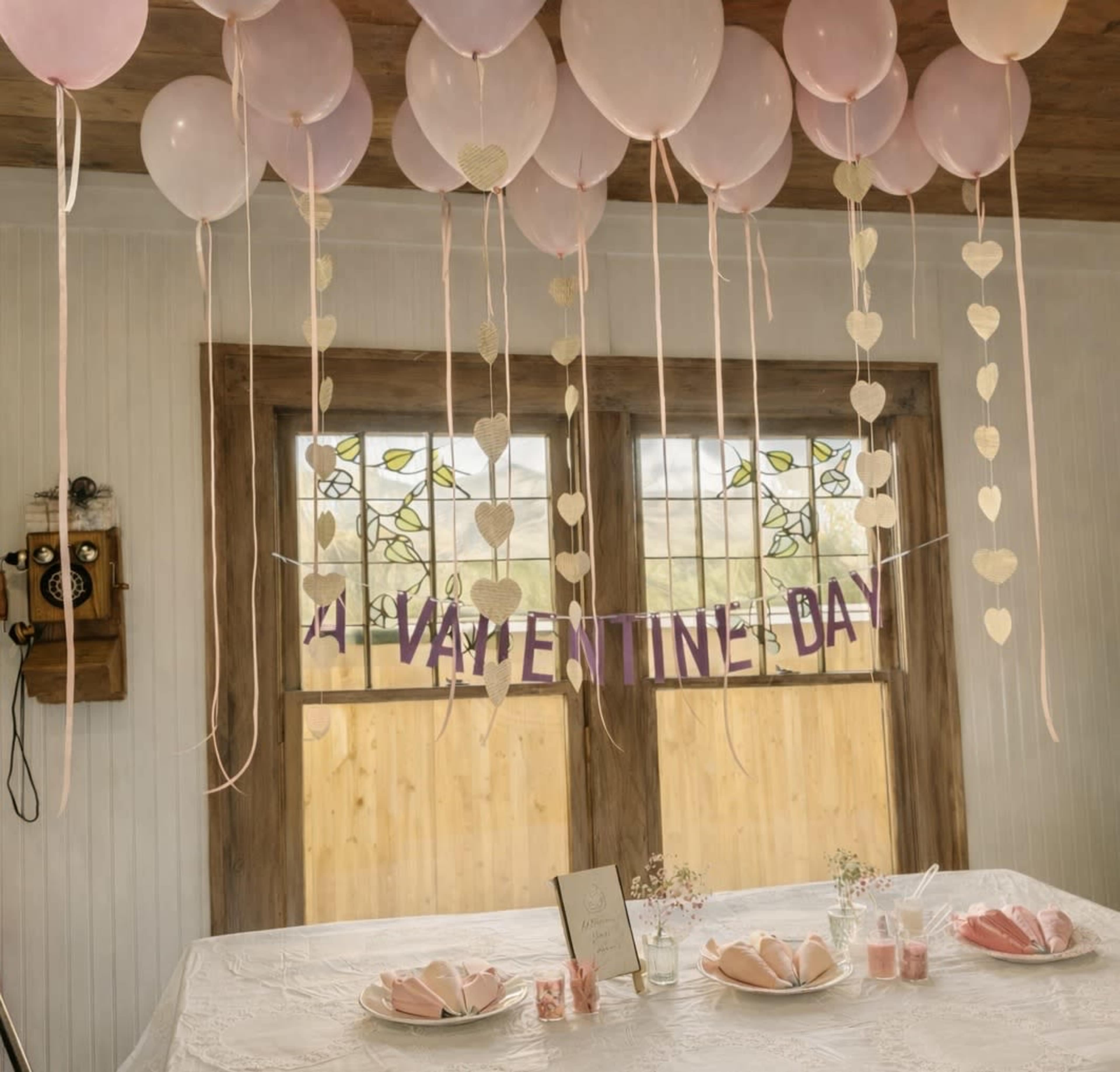 The scene features a decorated room with pink balloons, heart-shaped garlands, and a table set for Valentine's Day.