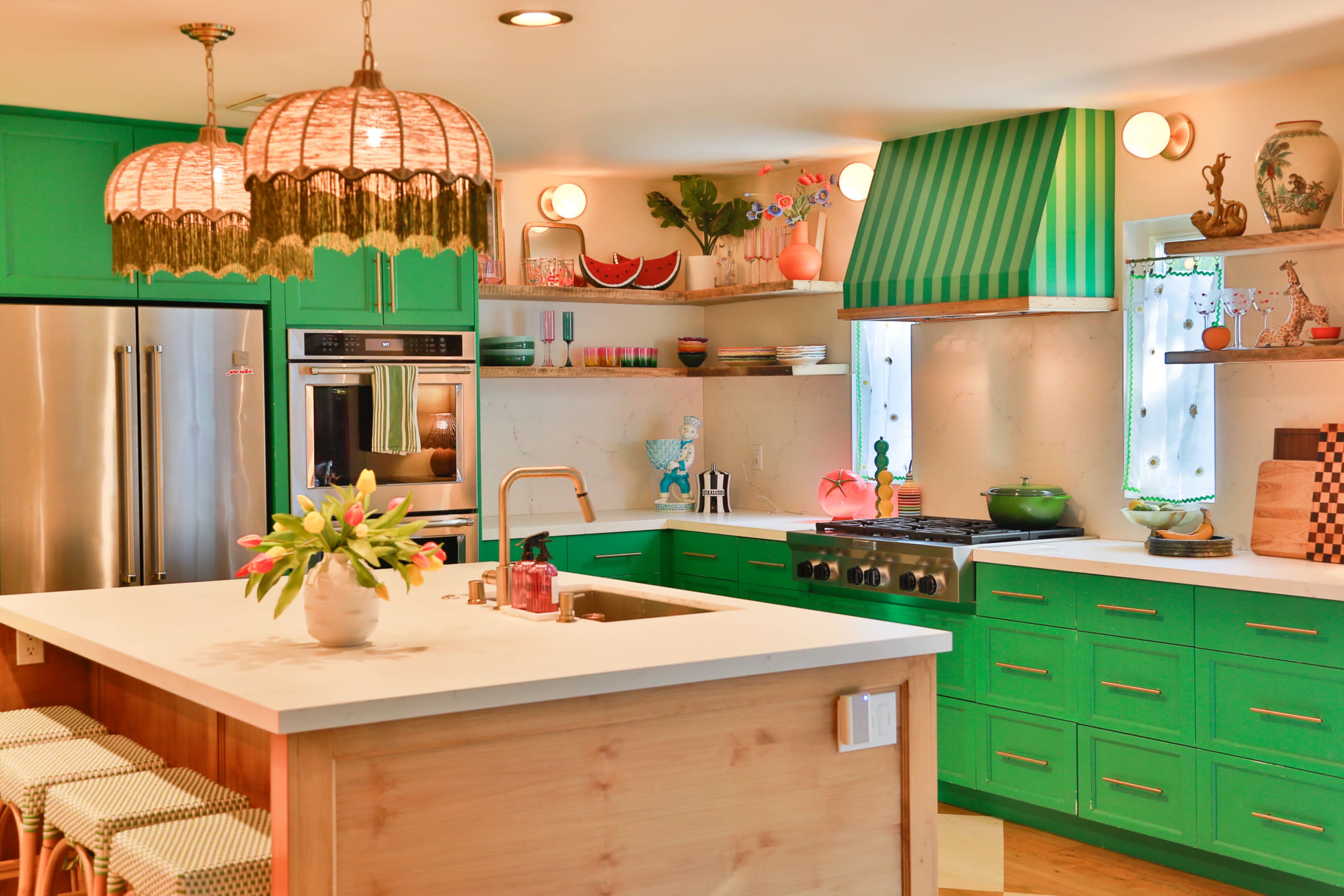 The kitchen features vibrant green cabinets, a white countertop, and modern appliances, accented by decorative items and a large island with seating.