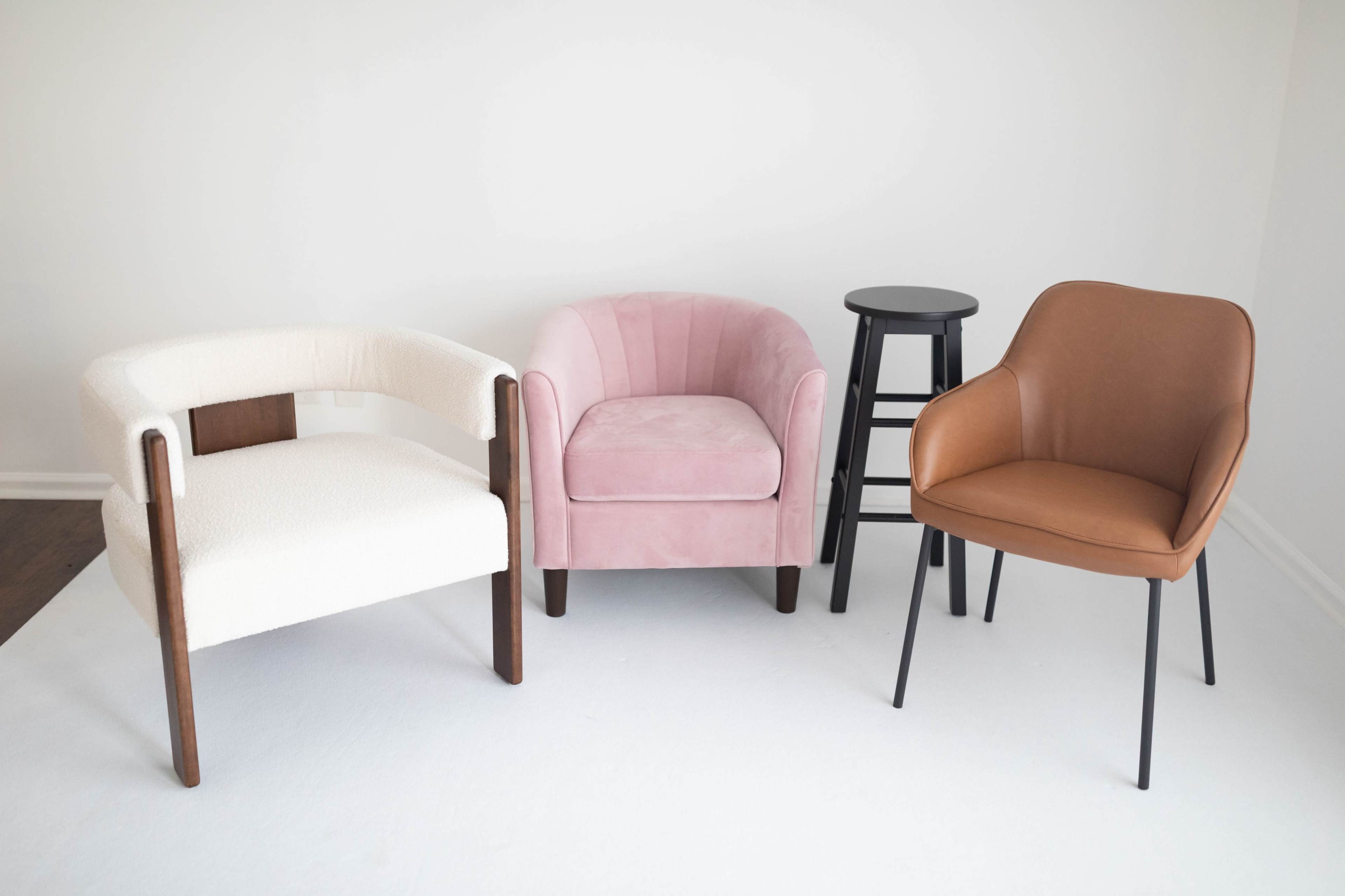 The image shows four chairs arranged in a minimalist setting with a white background.