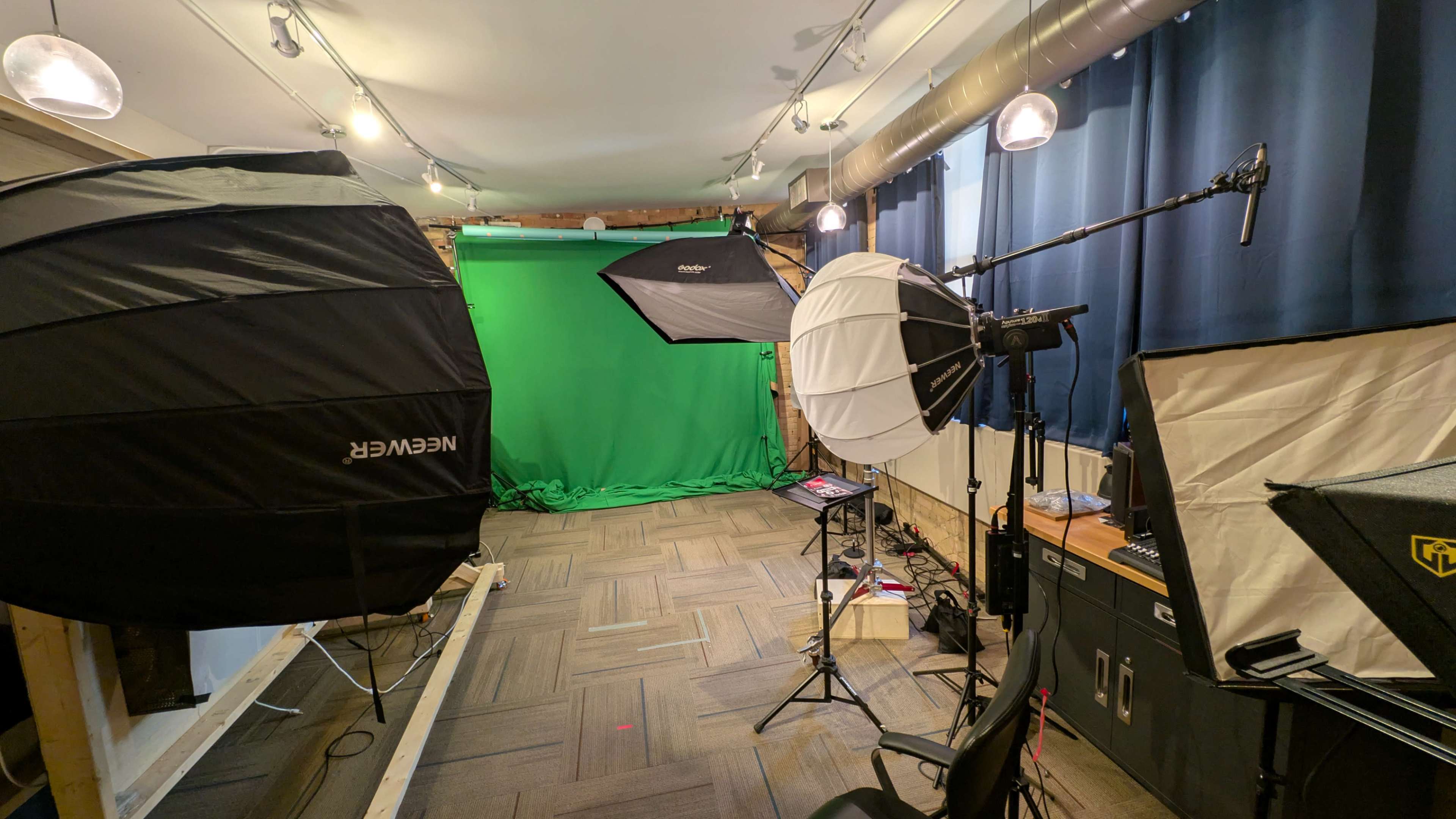The image shows a photography studio equipped with multiple lighting setups and a green screen backdrop.