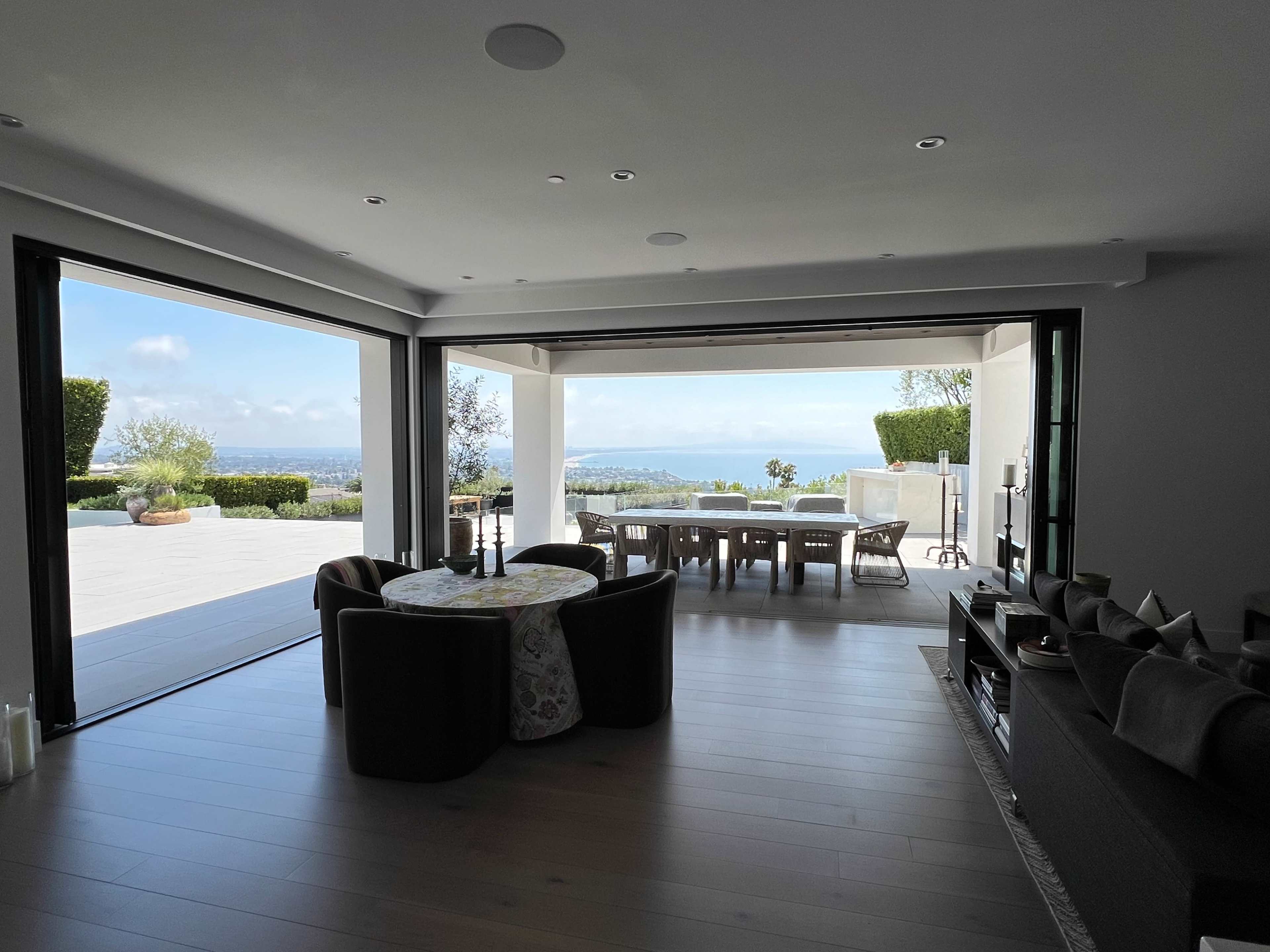 A modern living room features large sliding glass doors that open to a patio with a view of the landscape beyond.