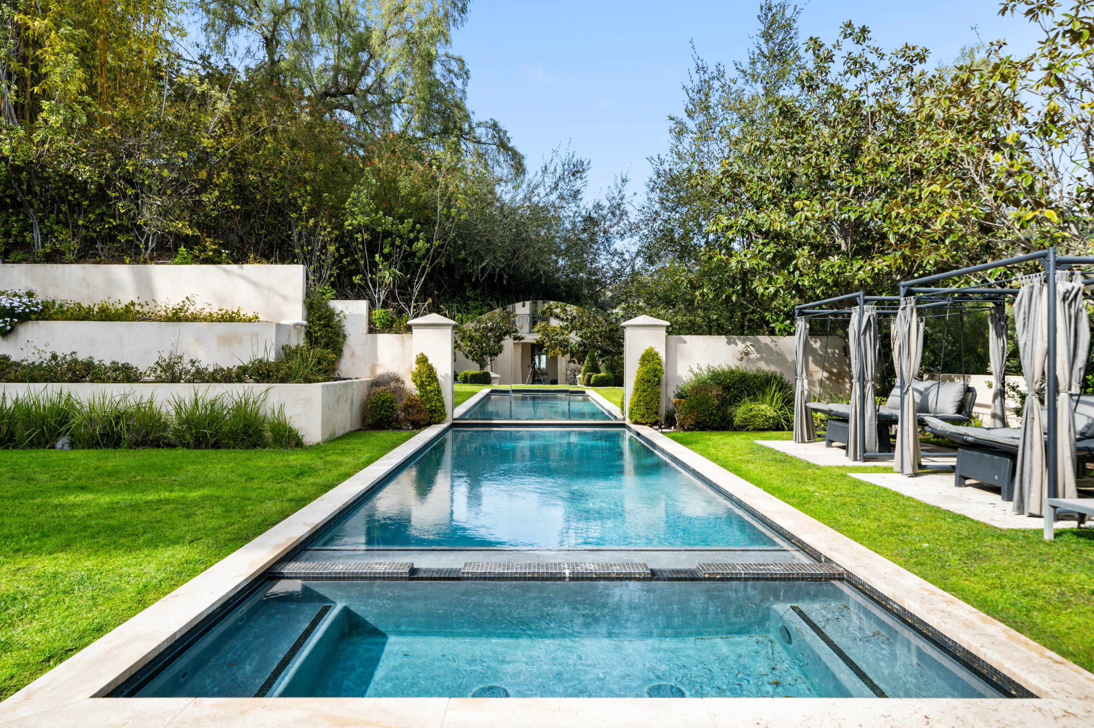 A sleek outdoor pool surrounded by landscaped gardens and shaded seating areas.