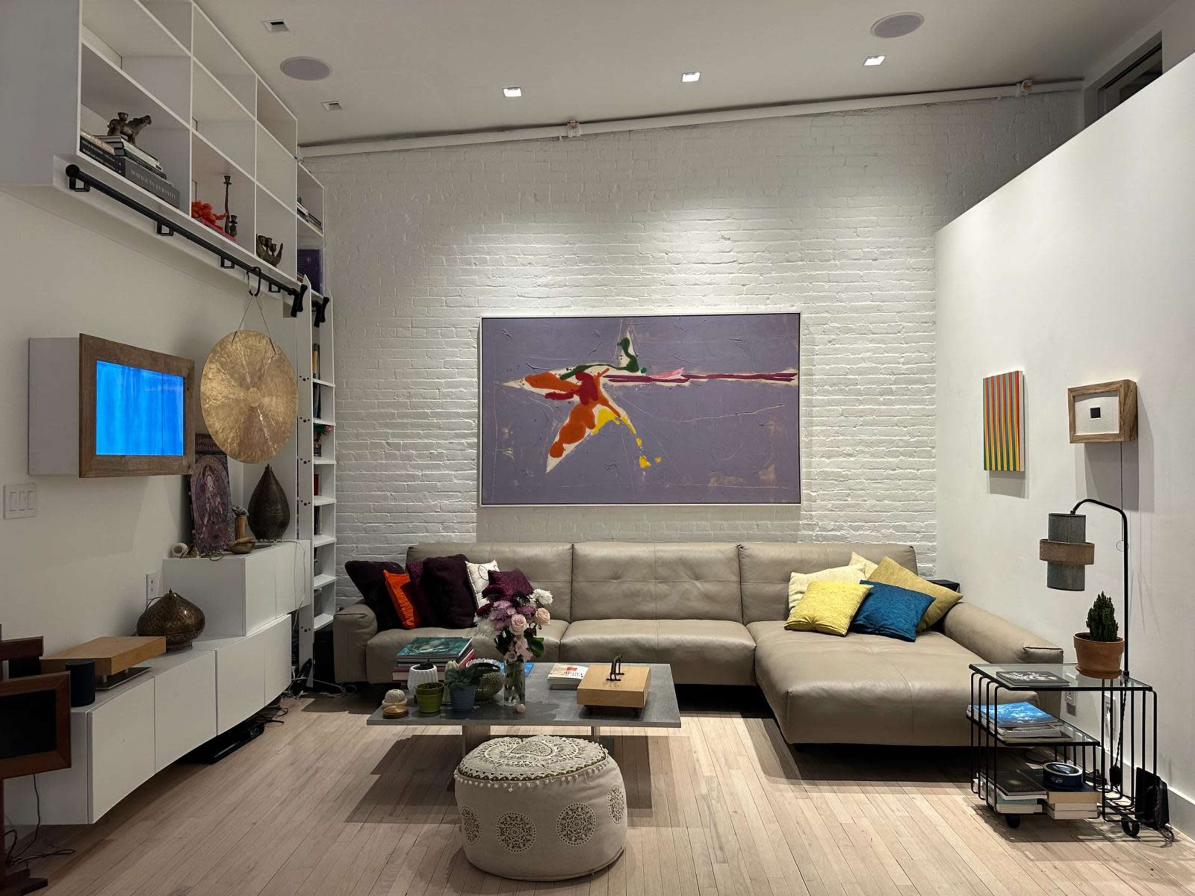 A modern living room with a large sectional sofa, a coffee table, and a vibrant painting on the wall.