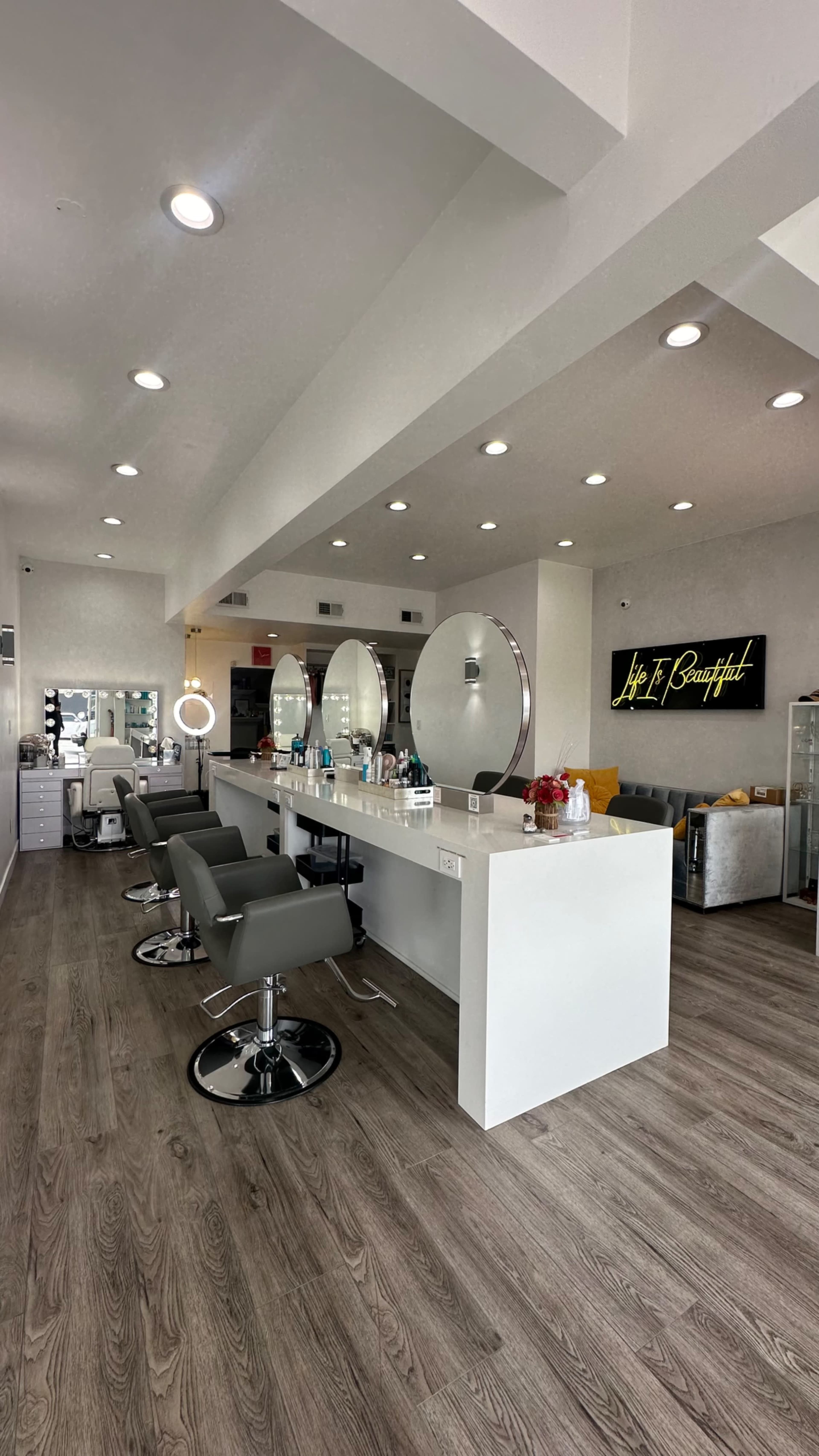 A modern hair salon with several styling stations, round mirrors, and sleek chairs.