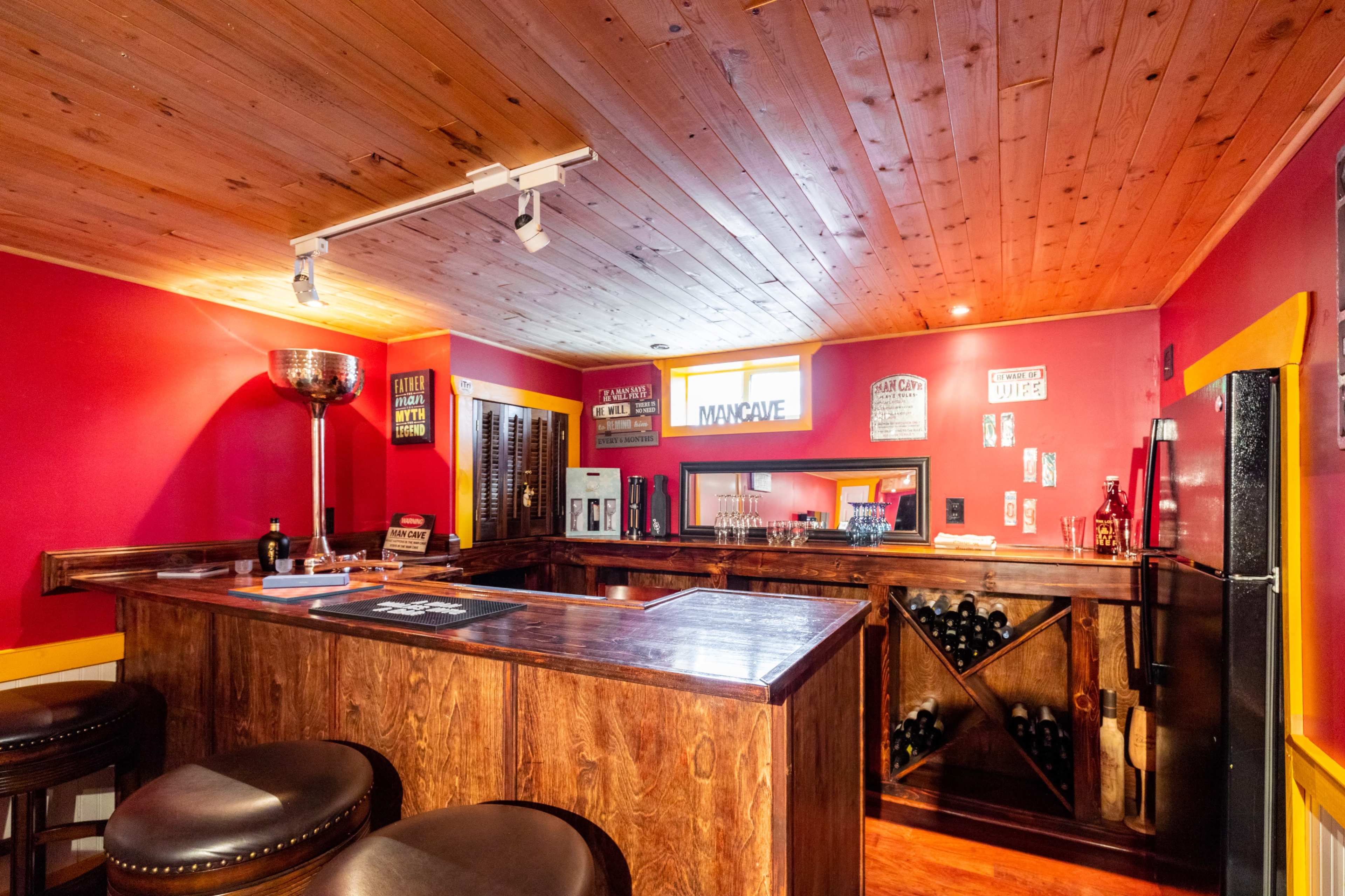 A warmly lit bar area with wooden paneling, a long counter, and various signs and decorations on the walls.