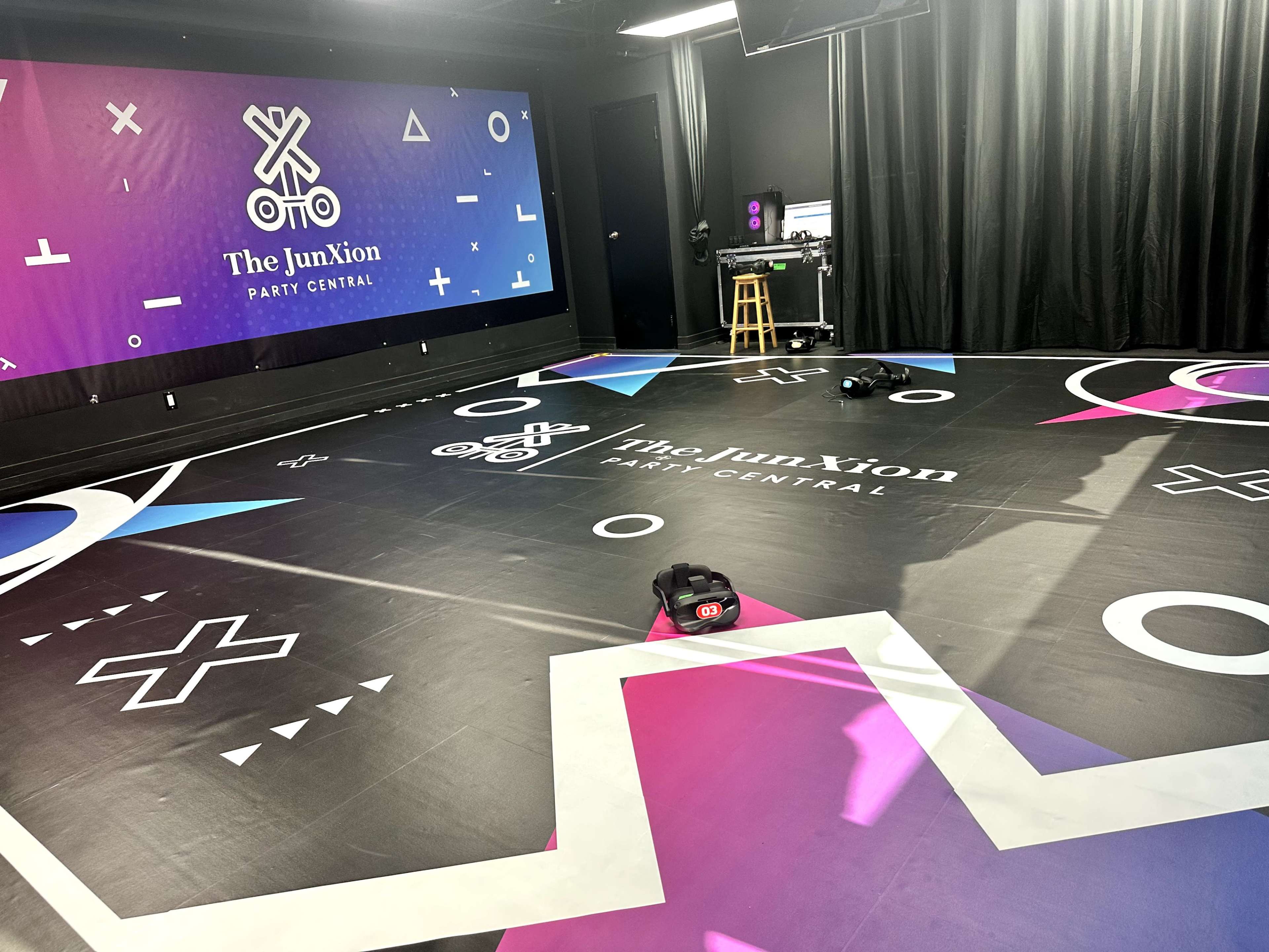 The image shows a brightly colored party venue with a large, patterned floor and a backdrop featuring the name "The JunXion Party Central."