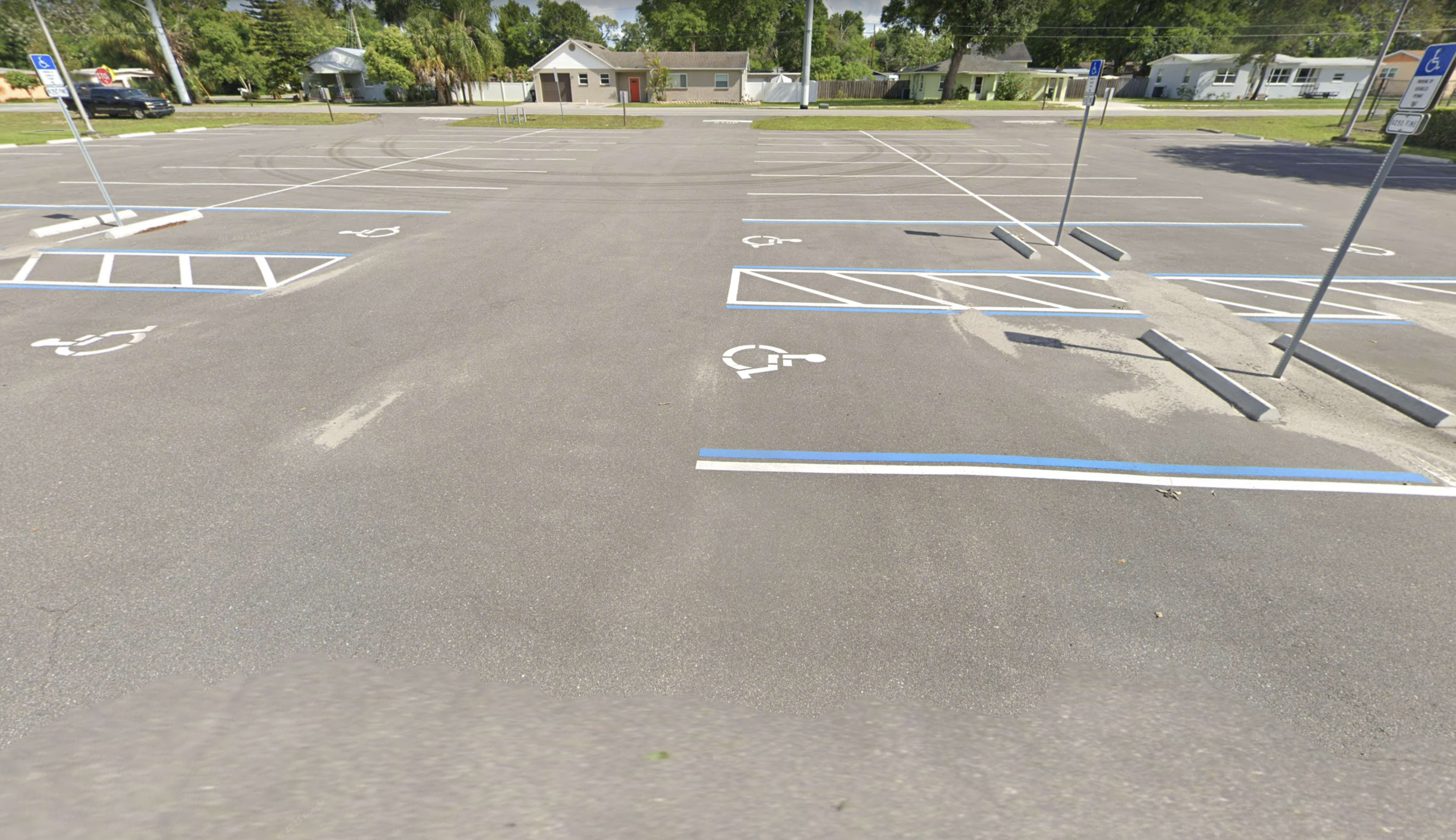 The image shows a mostly empty parking lot with several marked handicap parking spaces and a few empty stalls.