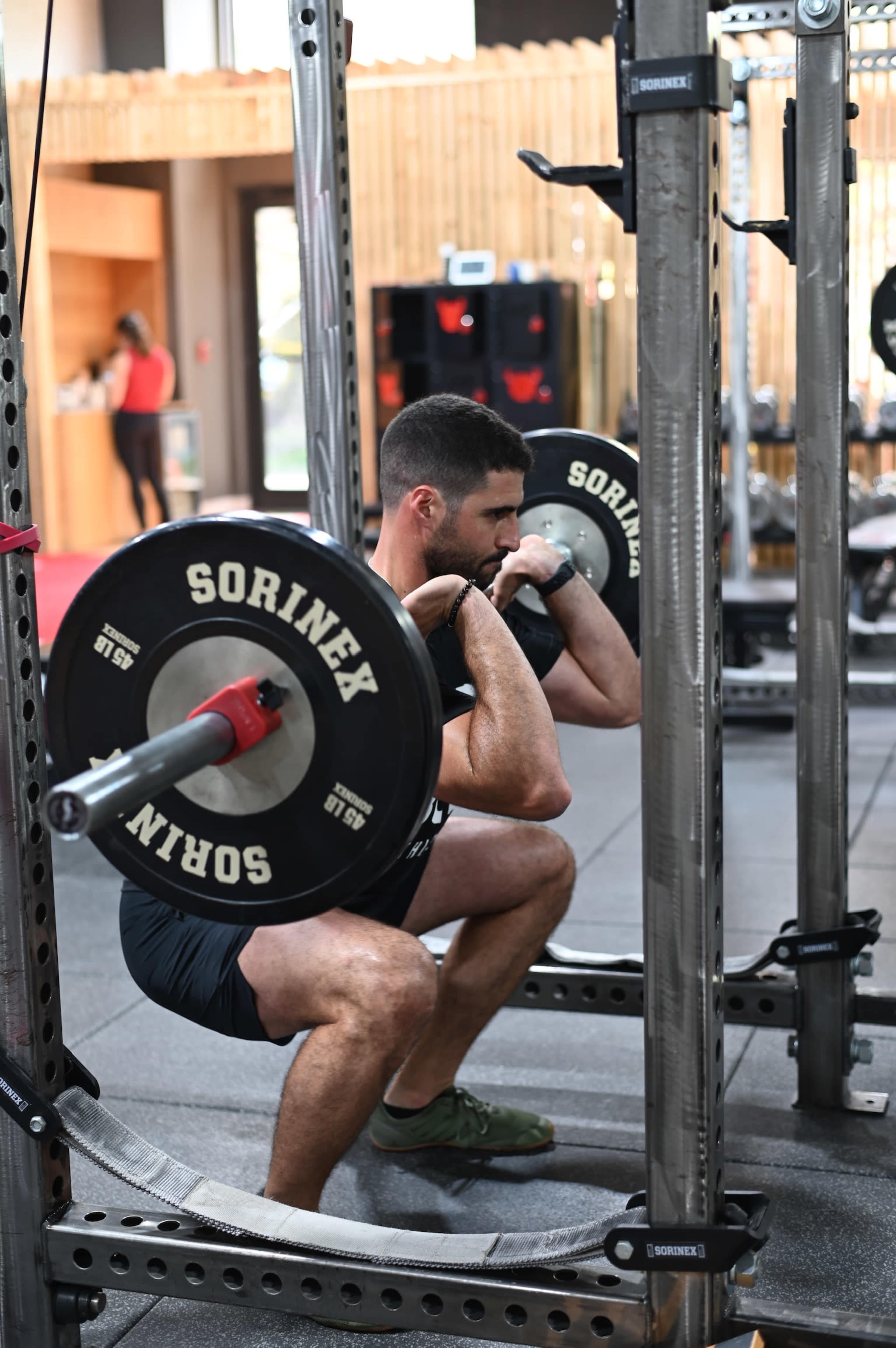 A man performs a squat with a barbell in a gym.