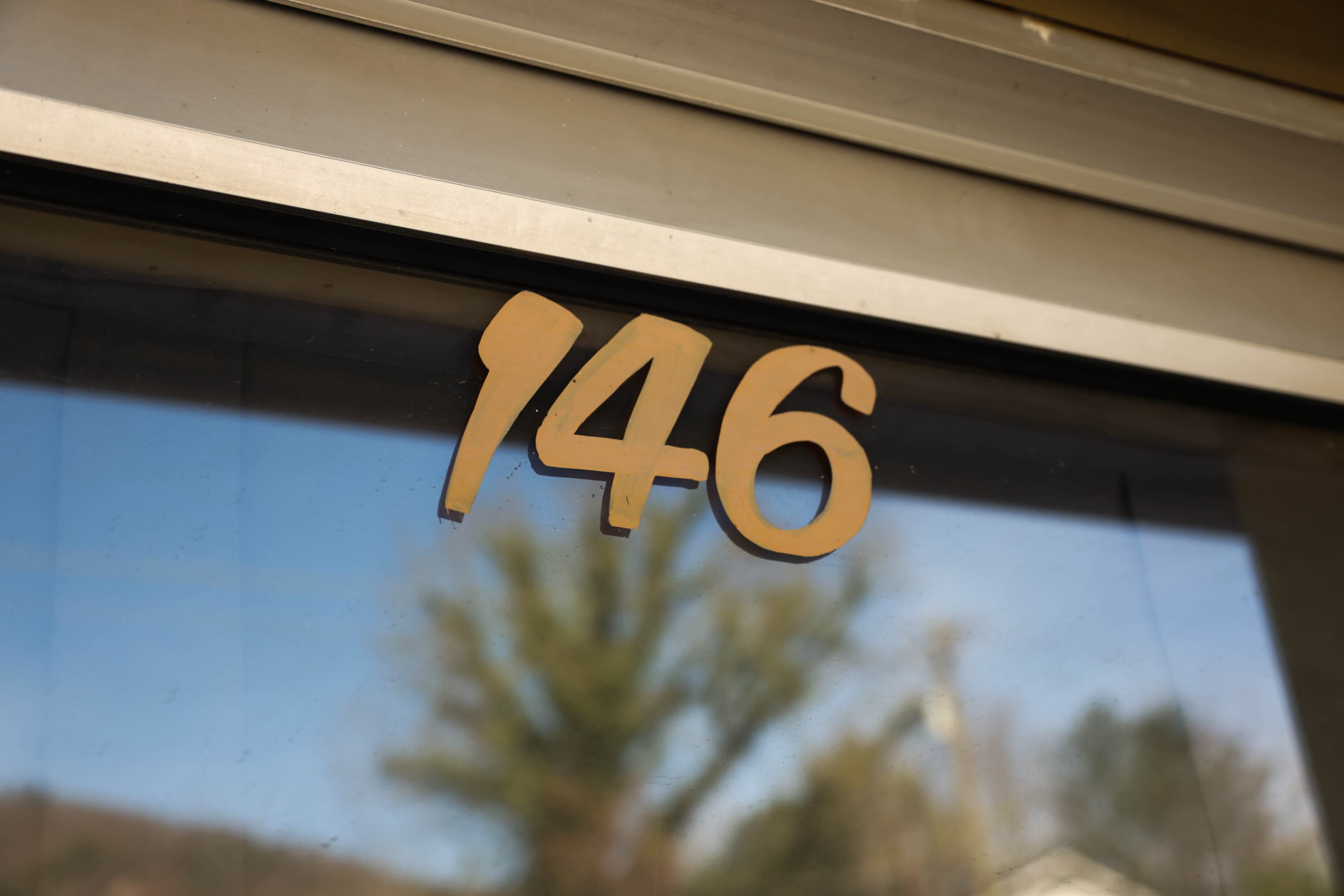 The image shows the number "146" displayed on a glass door.