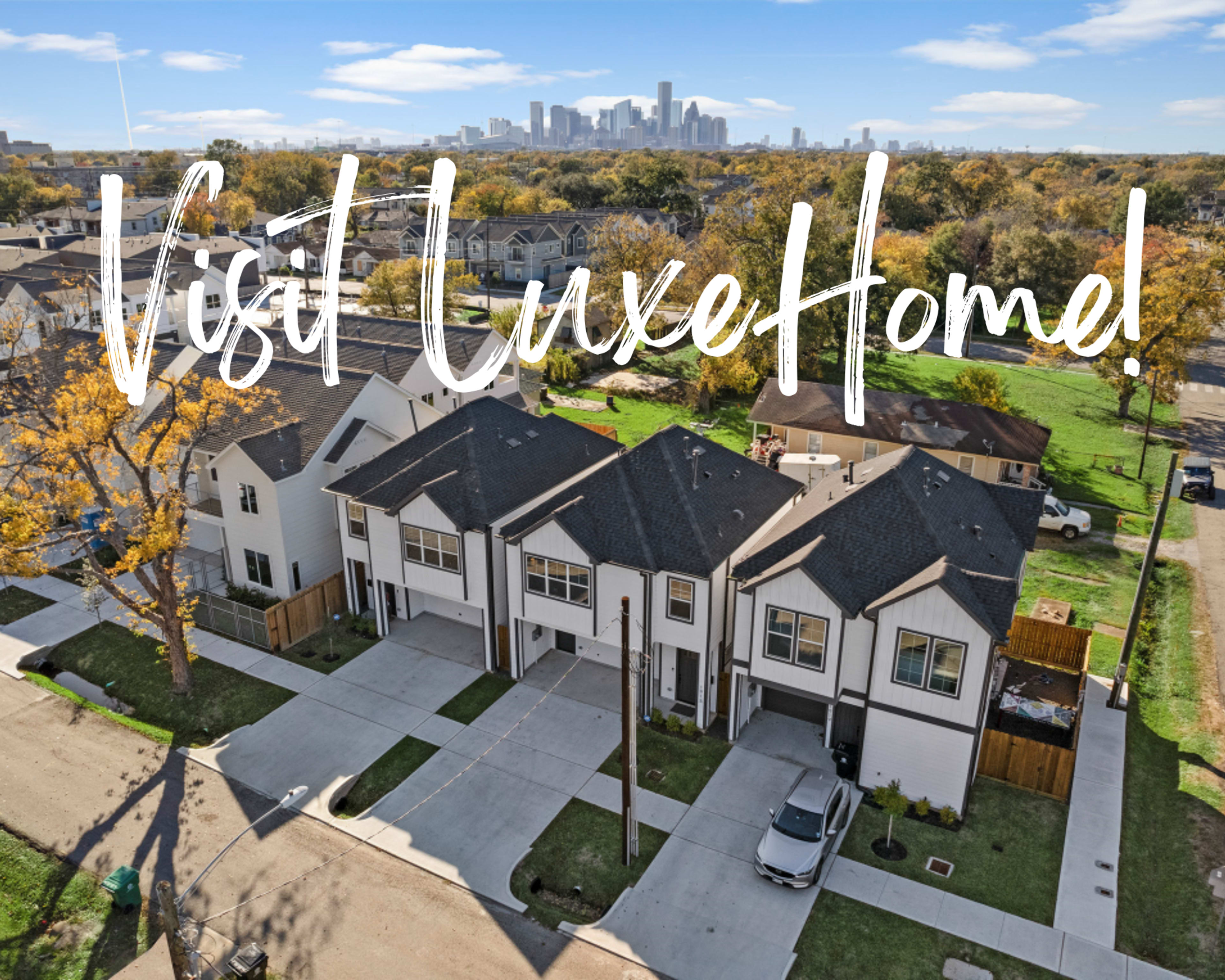 A row of modern townhouses in an urban area with a city skyline visible in the background.