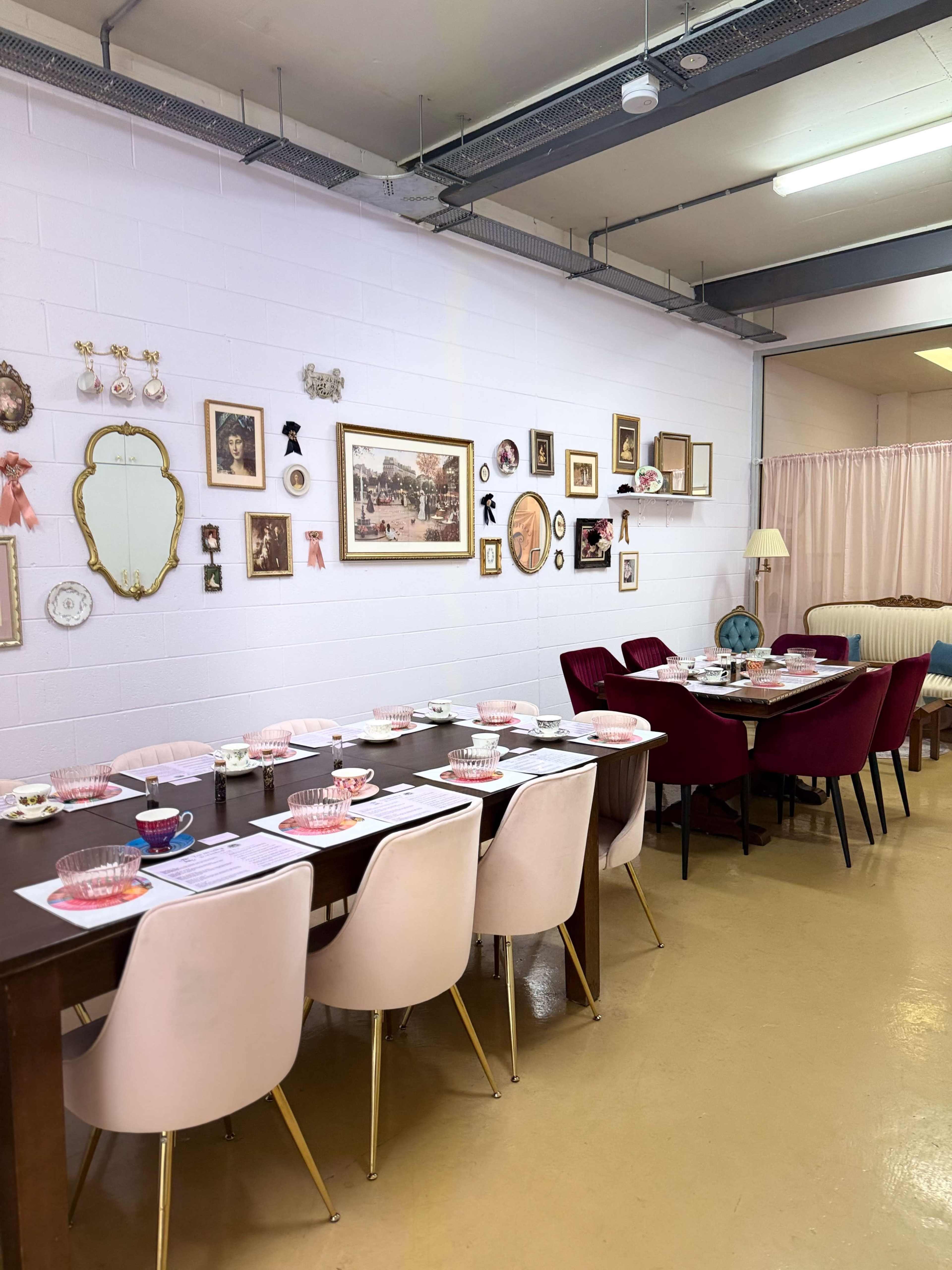 A long wooden dining table is set with dishes and utensils in a room decorated with various framed pictures and objects on the walls.