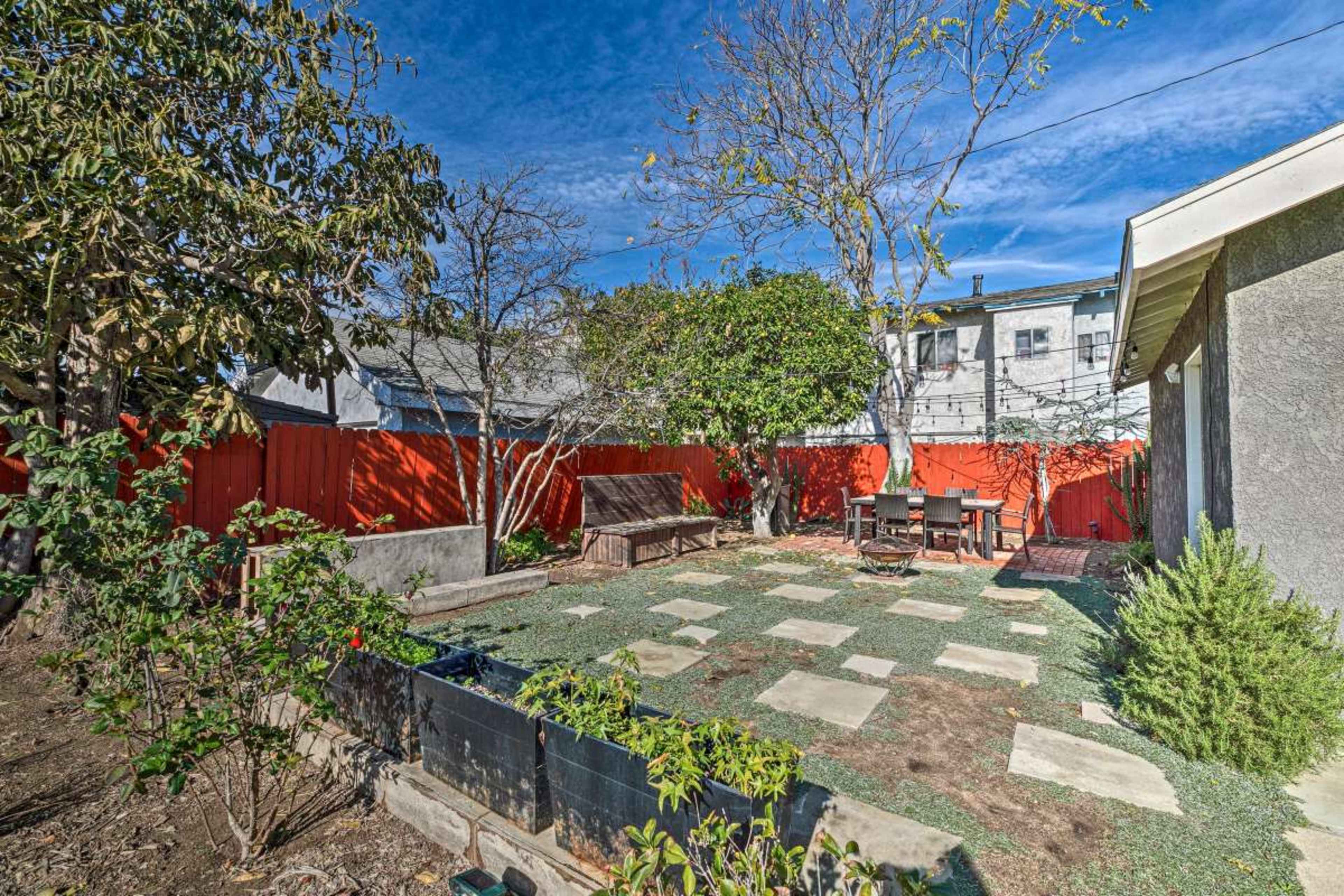 A backyard features a gravel area with stone pavers, surrounded by wooden fencing and sparse greenery.
