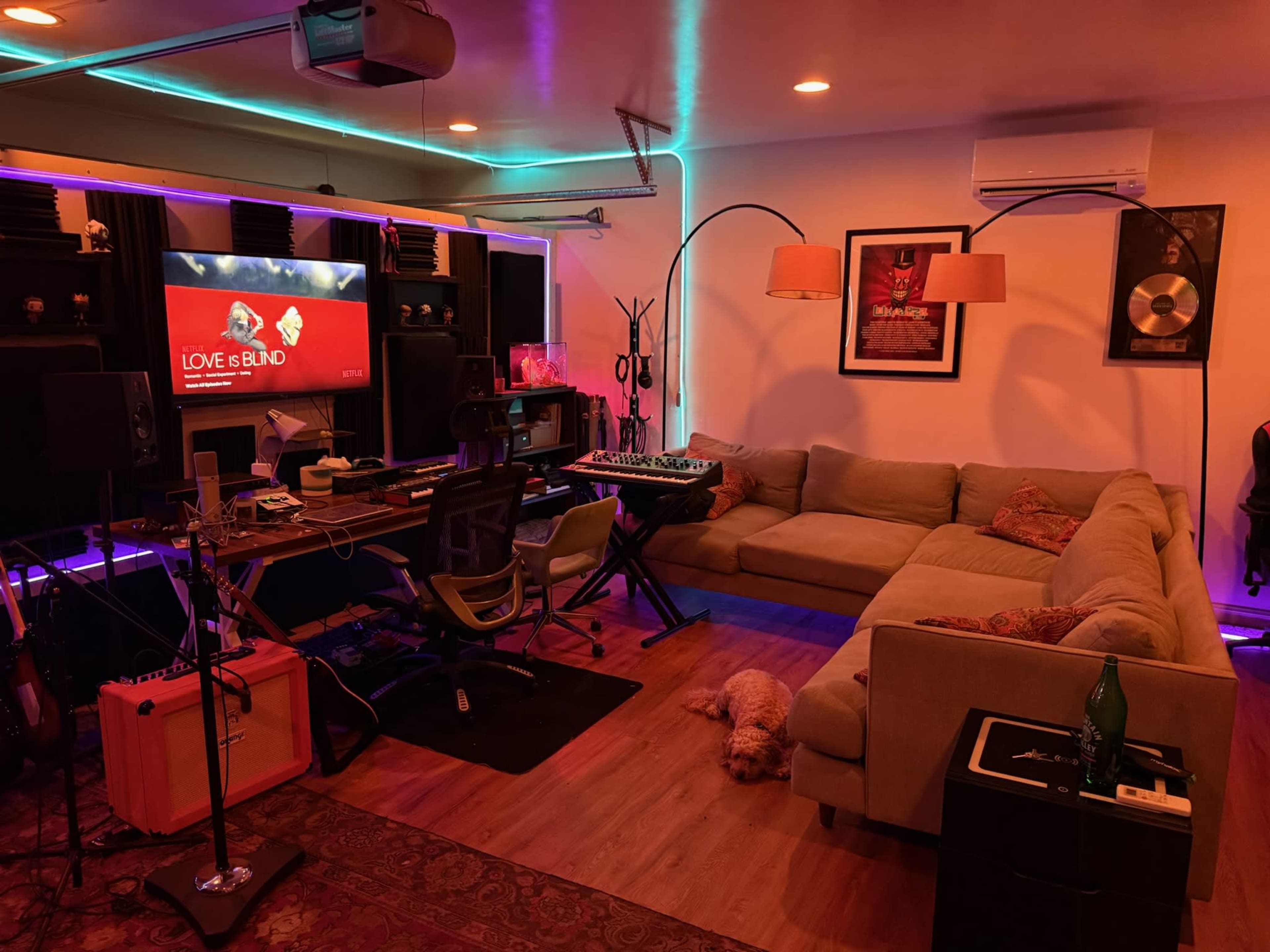 The image depicts a home recording studio with a cozy couch, audio equipment, and colorful lighting.