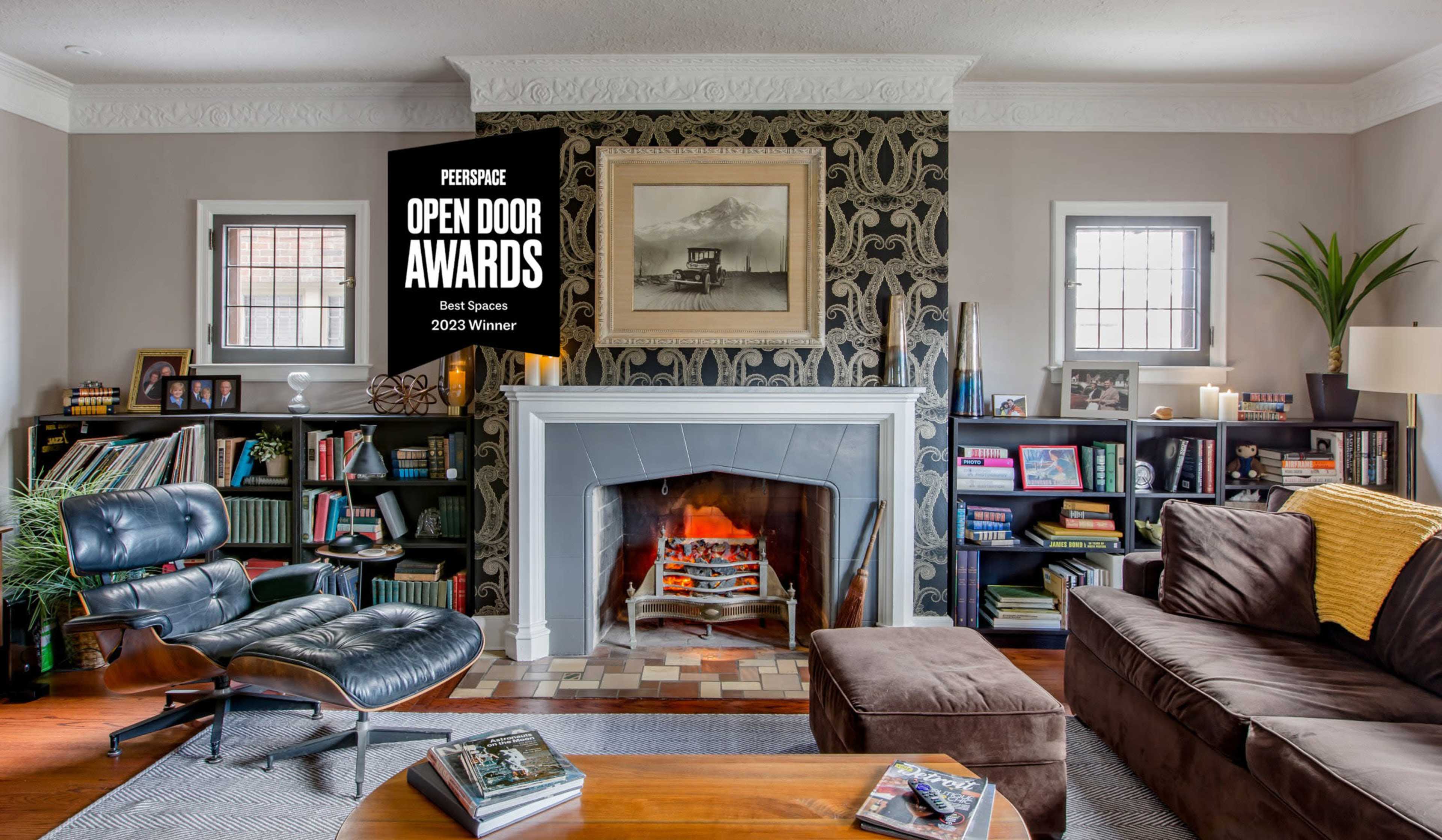 A cozy living room features a fireplace with a patterned wall behind it, surrounded by bookshelves filled with books and decorative items.