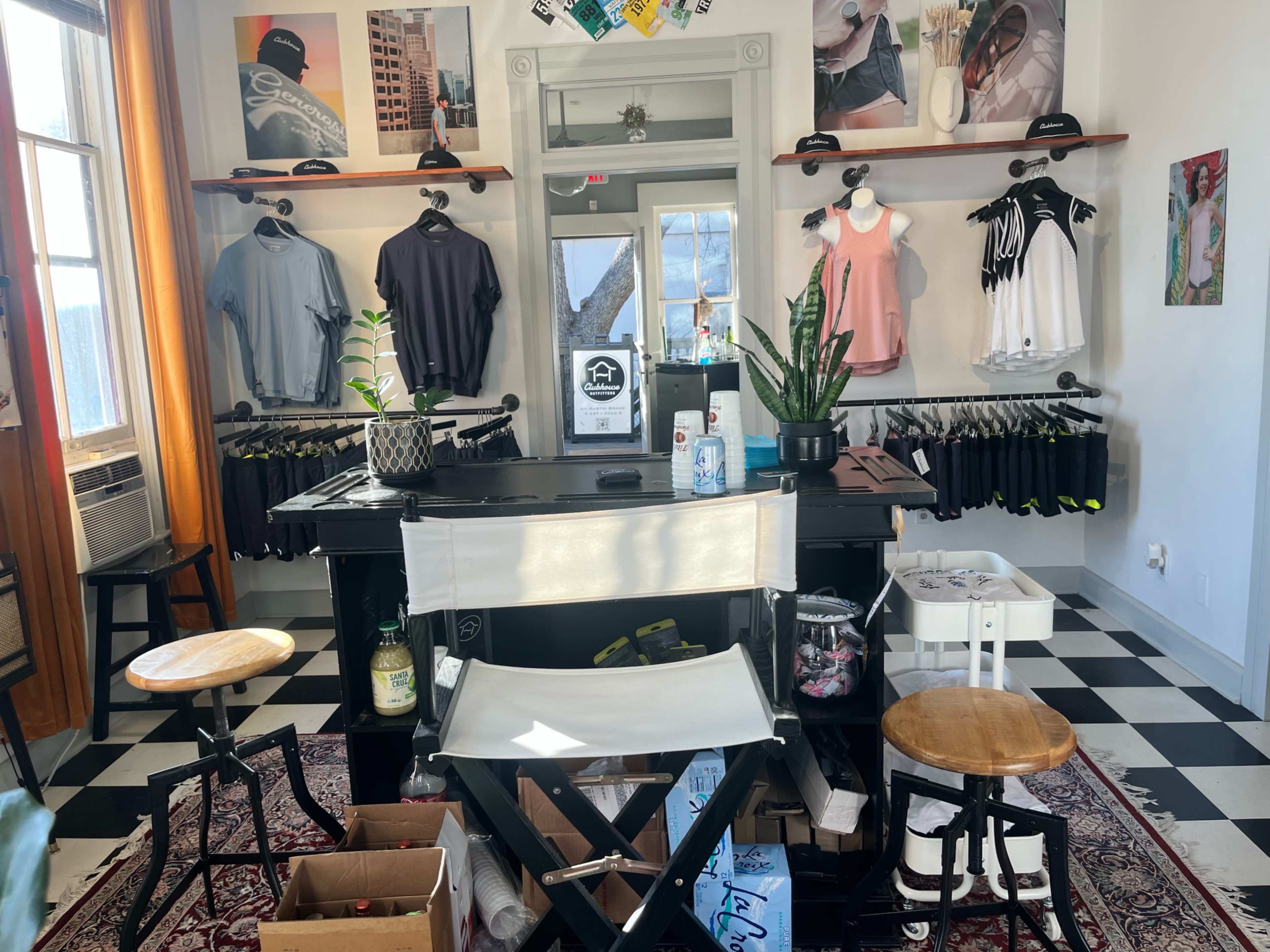 A retail space featuring clothing racks, a counter with various items, and a selection of apparel displayed on the walls.