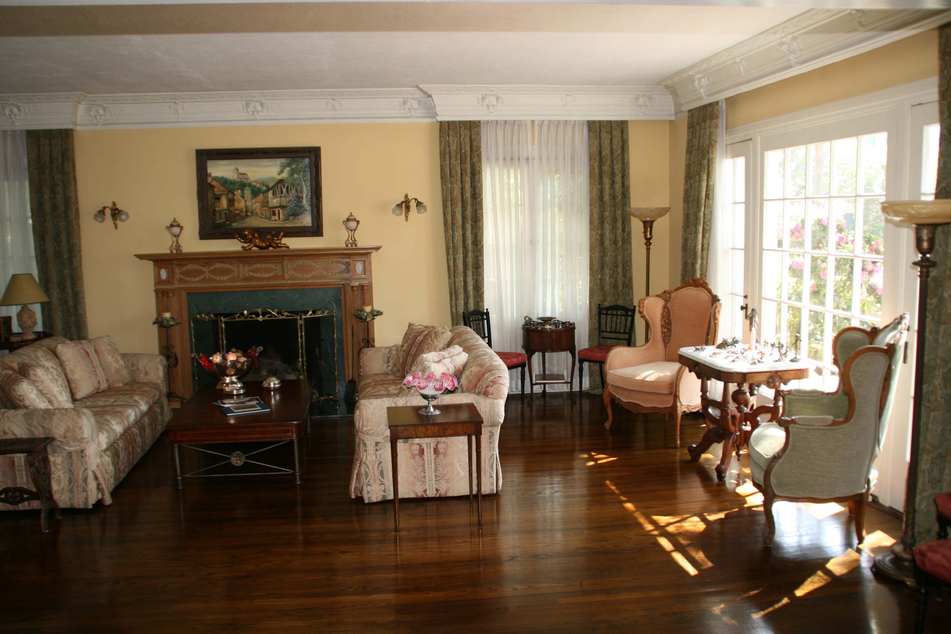 The living room features a fireplace surrounded by two sofas and a coffee table, with large windows that let in natural light.